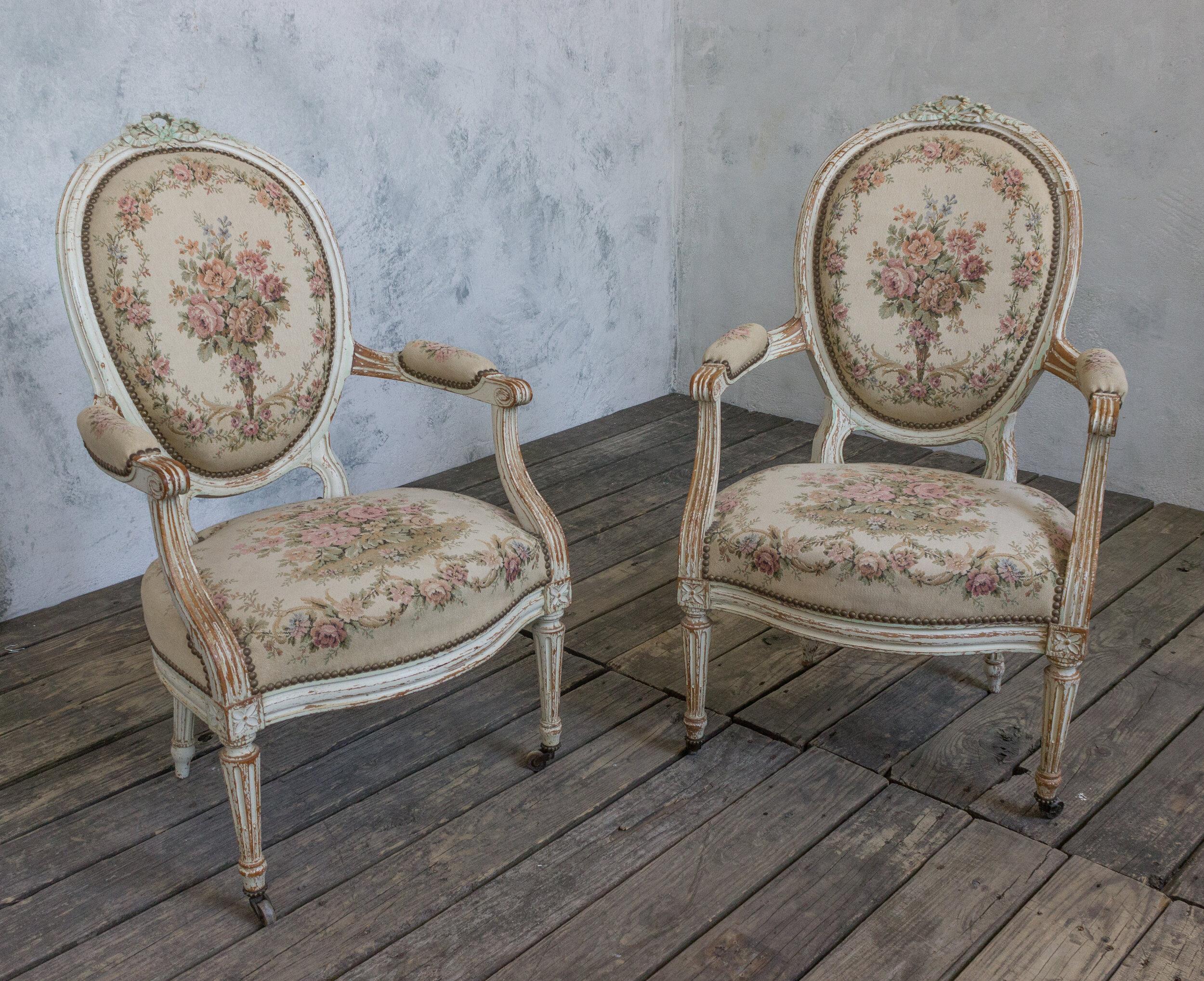 An exquisite pair of French Louis XVI style armchairs. Elevate your décor to the heights of luxury and elegance with this classic pair of 19th century French armchairs. Crafted in white washed, patinated frames rich with intricate carvings and