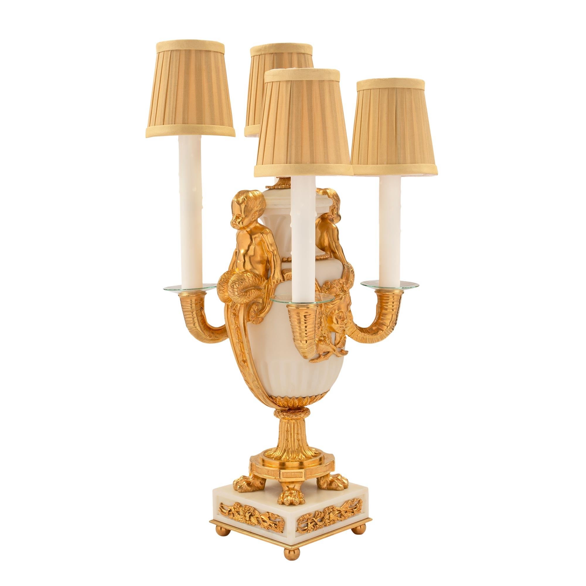 Paire de lampes candélabres électrifiées à quatre bras en marbre de Carrare blanc et bronze doré, probablement d'Henry Dasson, d'époque Louis XVI et Belle Époque. Chaque lampe est surélevée par une base carrée en marbre de Carrare blanc avec des
