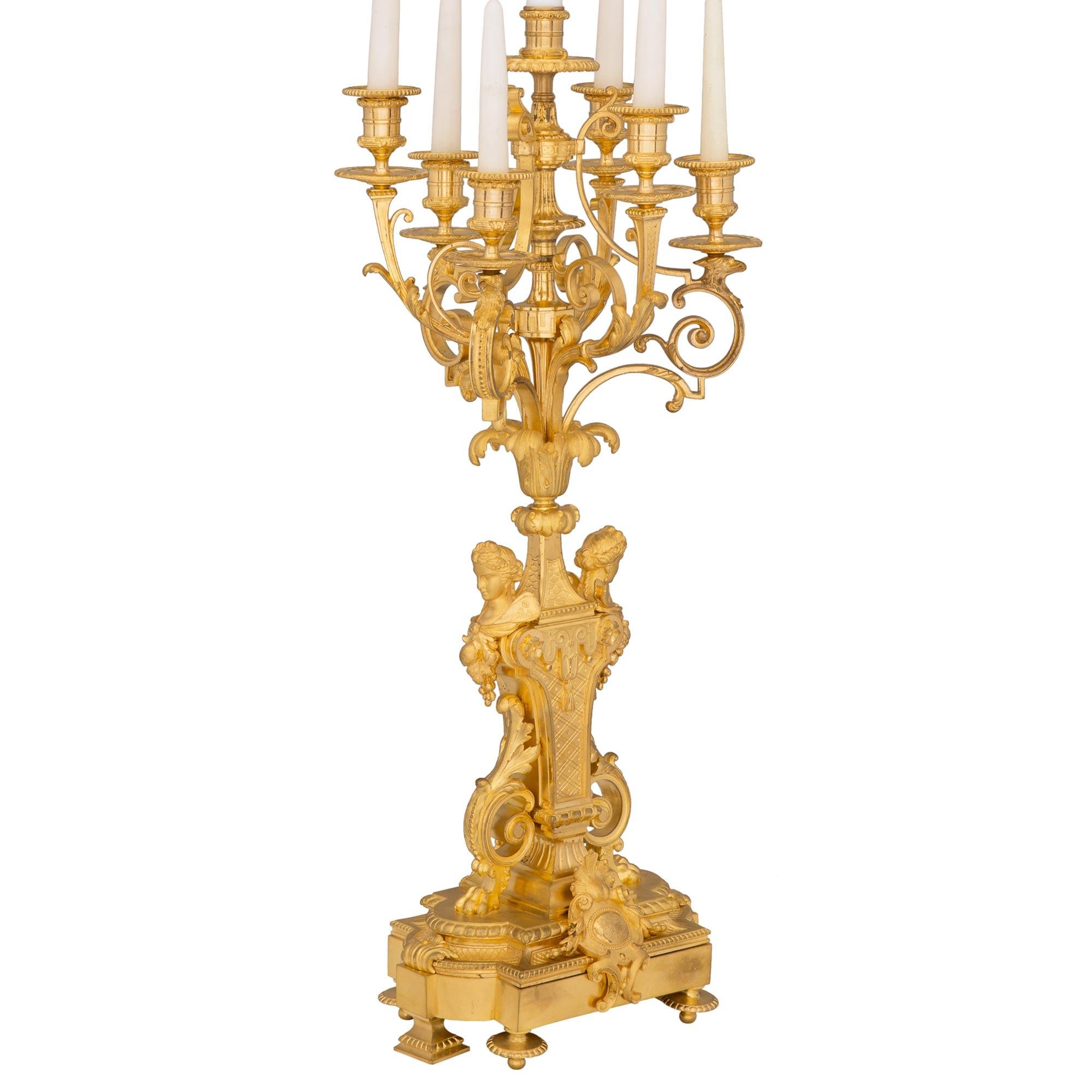 An exceptional and unique pair of French 19th century Louis XVI st. Belle Époque period ormolu six arm candelabra lamps. Each lamp is raised by elegant topie shaped feet and square tapered supports below a mottled border. At the center are