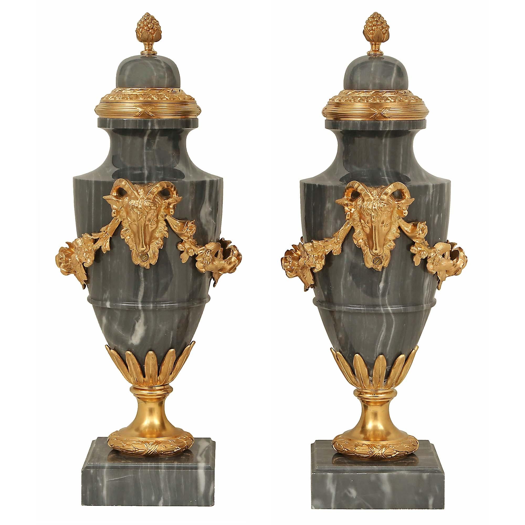 Una straordinaria coppia di urne francesi del XIX secolo in marmo turchino blu e ormeggio. Ogni urna è sollevata da una base quadrata in marmo con un bordo screziato e da un piedistallo a scialle satinato e brunito in ormù con una fascia di alloro