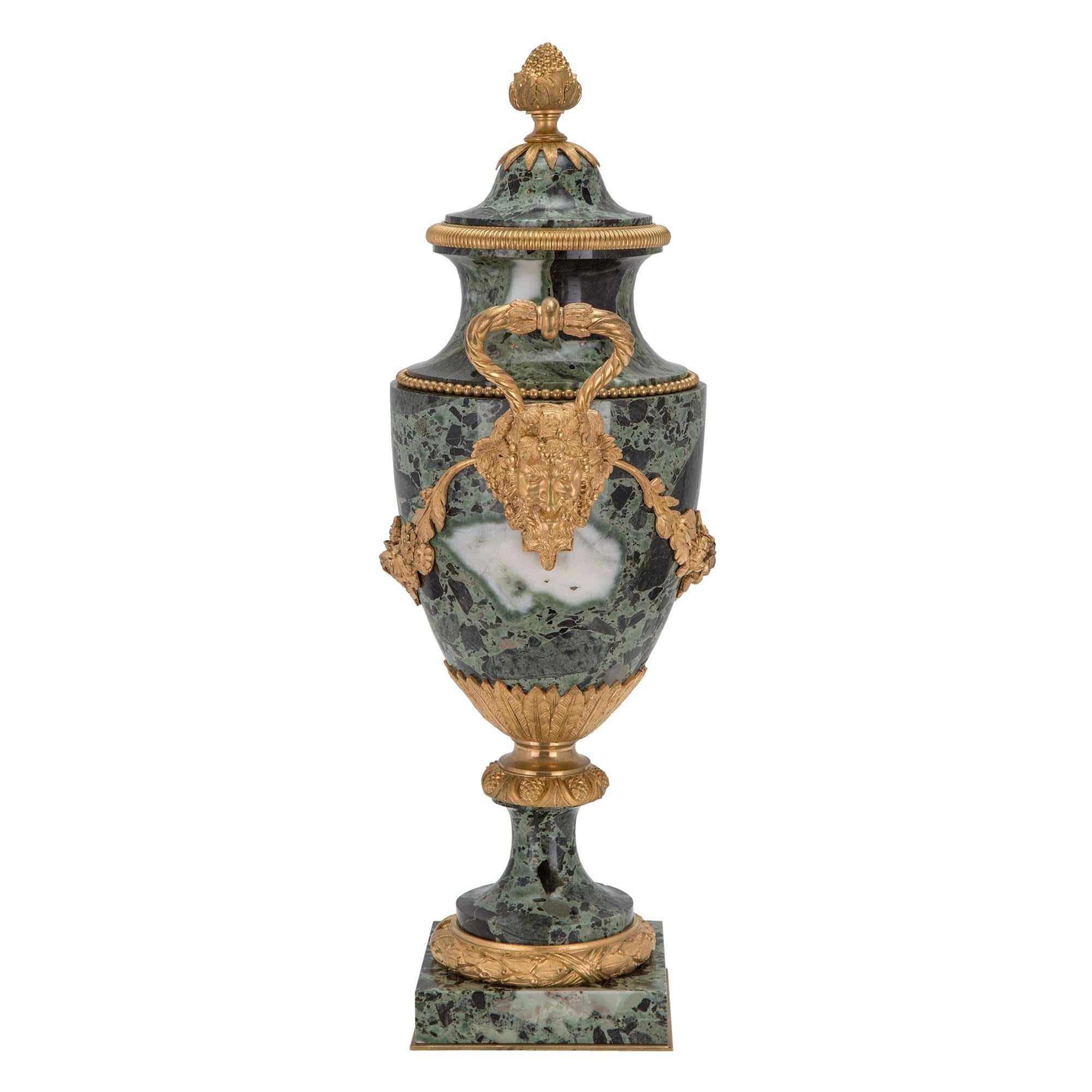 A superb pair of French 19th century Louis XVI st. Bréche Verte marble and ormolu urns. Each is raised on a square marble base with ormolu trim and ormolu laurel wreath above. The body is raised on a marble socle and is decorated by large ormolu