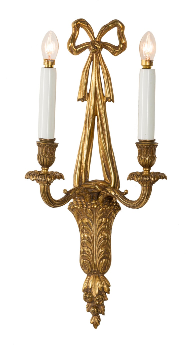 These 19th century French bronze wall sconces or appliqués display a variety of the neoclassical elements found in the Louis XVI style. The central vertical of the sconces is in the form of a cornucopia decorated with acanthus leaves, from which the