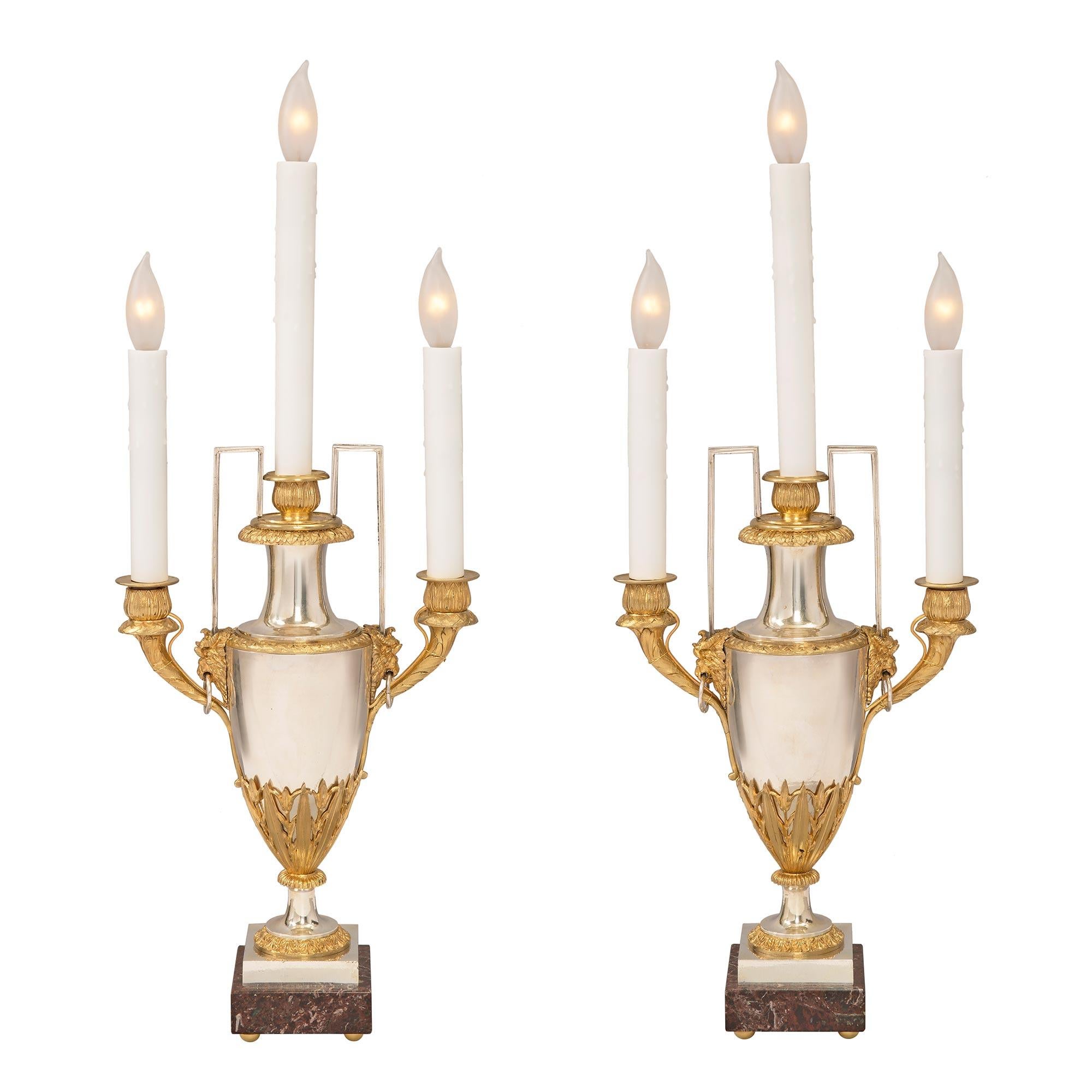 A most elegant pair of French 19th century Louis XVI st. silvered bronze, ormolu and marble three arm candelabra lamps. Each lamp is raised by fine ormolu ball feet below a rectangular marble base. The ormolu socle pedestal displays a beautiful