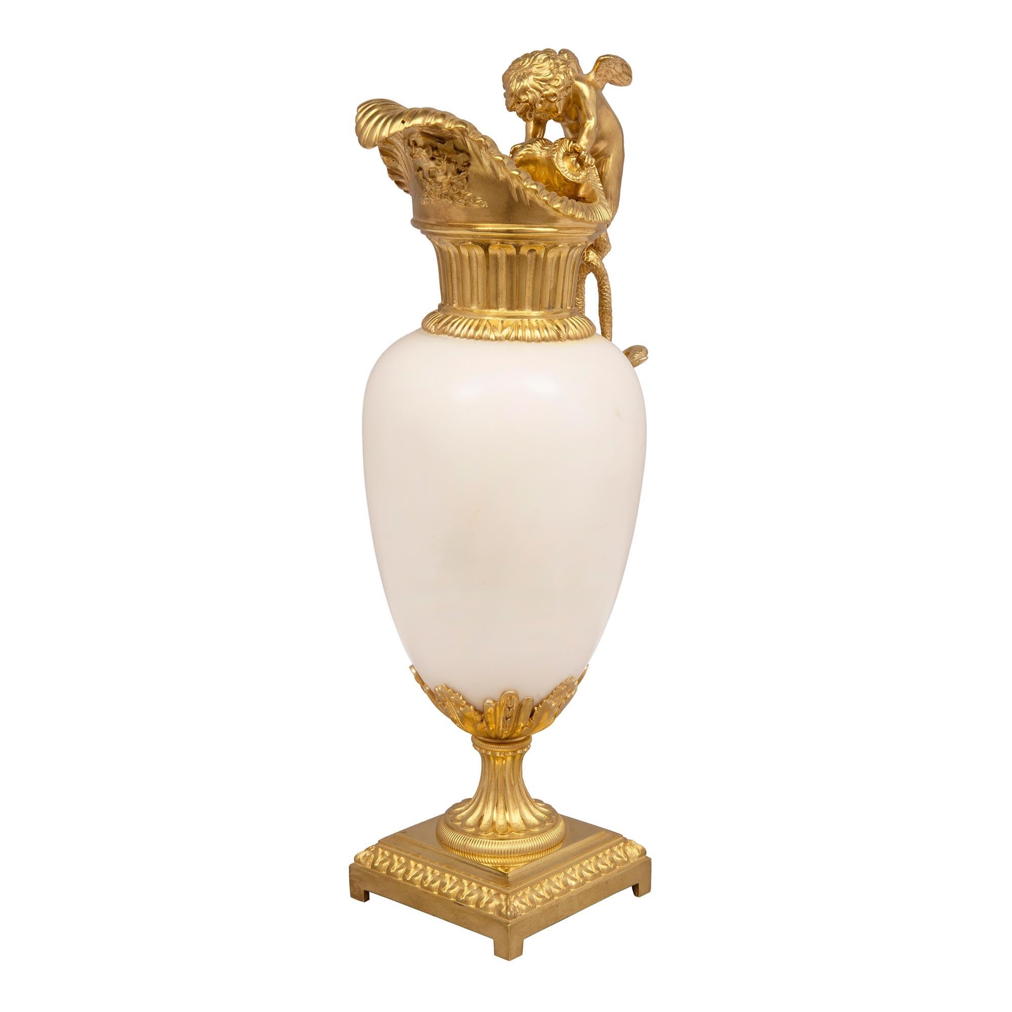 A stunning pair of French 19th century Louis XVI st. white carrara marble and ormolu ewers attributed to Henry Dasson. Each ewer is raised by square ormolu bases with fine block feet and a foliate wrap around bands. Above the fluted socle pedestals