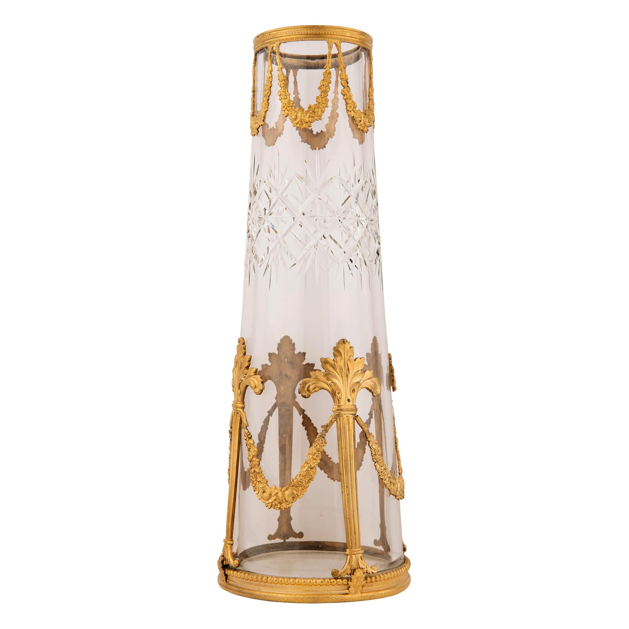 Une paire exquise de vases en cristal et bronze doré de style Louis XVI du 19ème siècle. Chaque vase en cristal de forme circulaire conique présente un magnifique cristal taillé en épaisseur avec des motifs en forme de diamant. Chaque vase s'effile