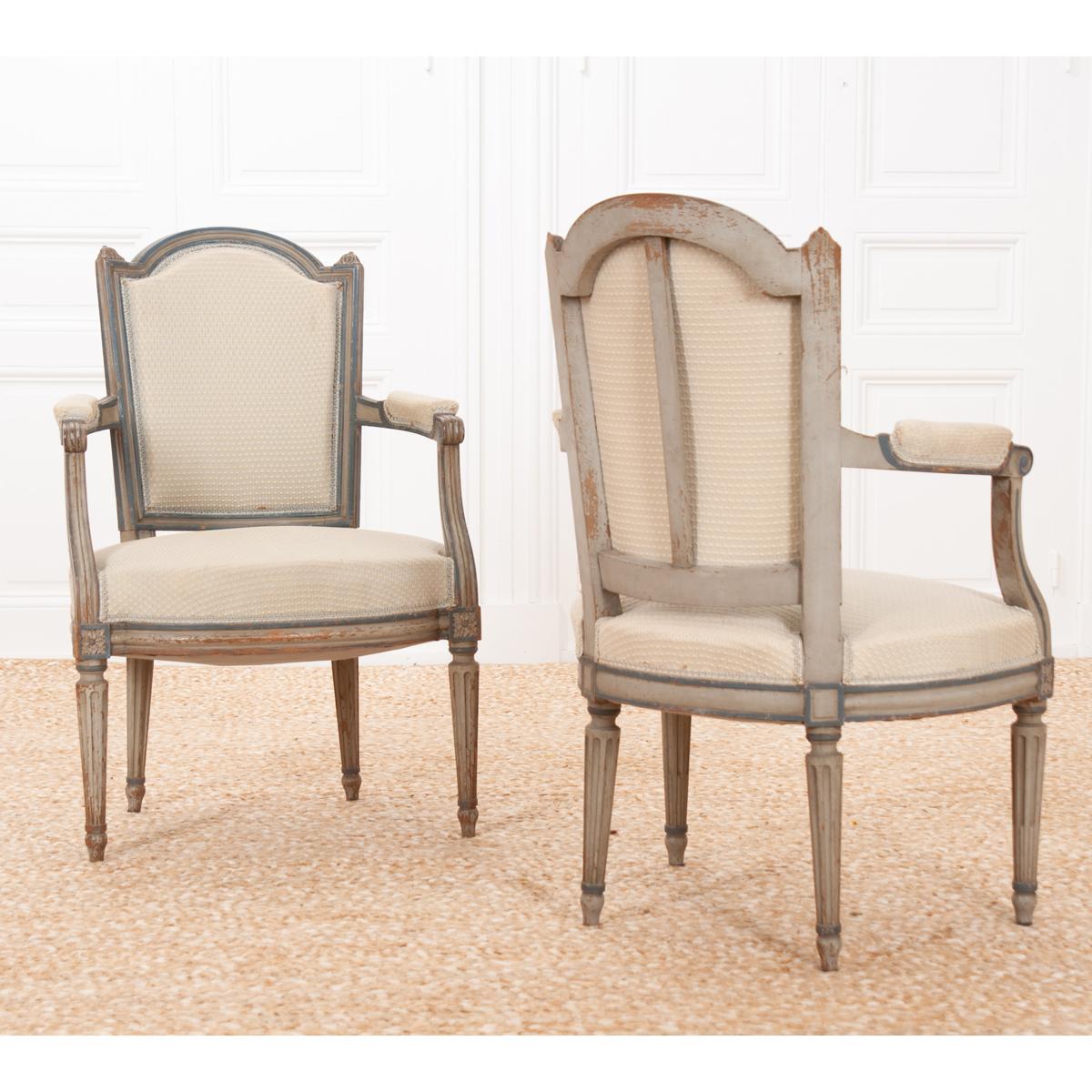 A lovely pair of painted fauteuils, upholstered in antique fabric. The armchairs are beautifully carved and painted, with both the paint and hardwood acquiring an exceptional patina over time. The frame sports an antiqued light gray/blue paint with