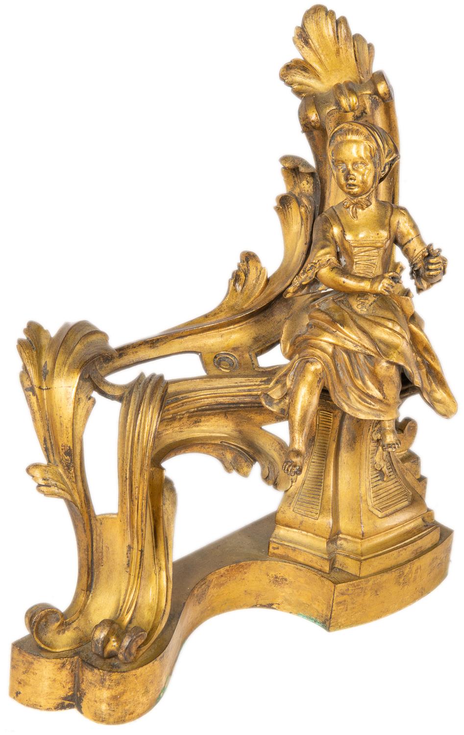 A very good quality pair of classical Rococo style 19th century French gilded ormolu chenets, each with scrolling foliate decoration with a young boy and girl seated.