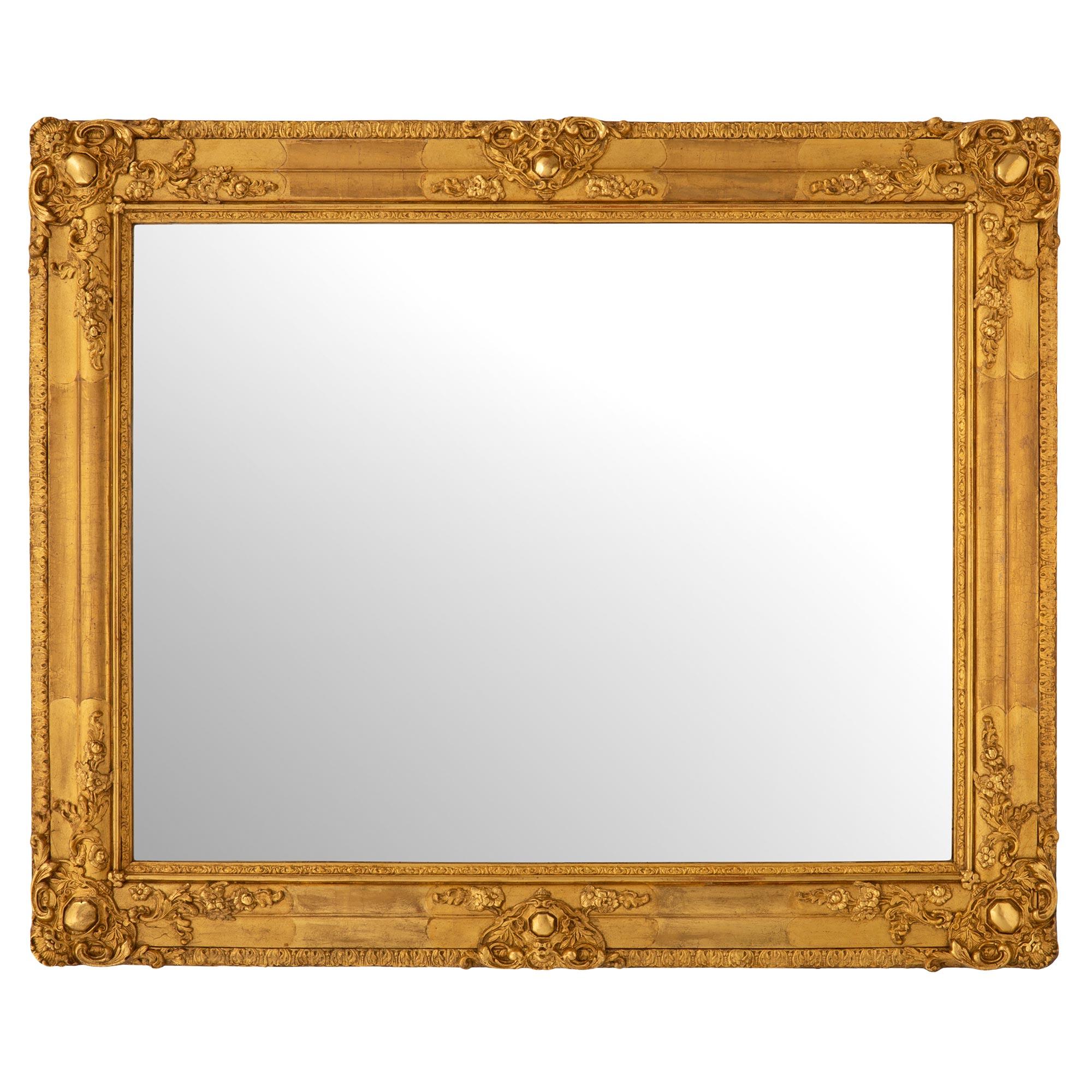 Paire de miroirs en bois doré de style Louis XVI du XIXe siècle. Chaque miroir conserve sa plaque d'origine encadrée d'une bordure en bois doré richement sculptée, dans une finition satinée et brunie. Chaque élégant cadre en bois doré présente une