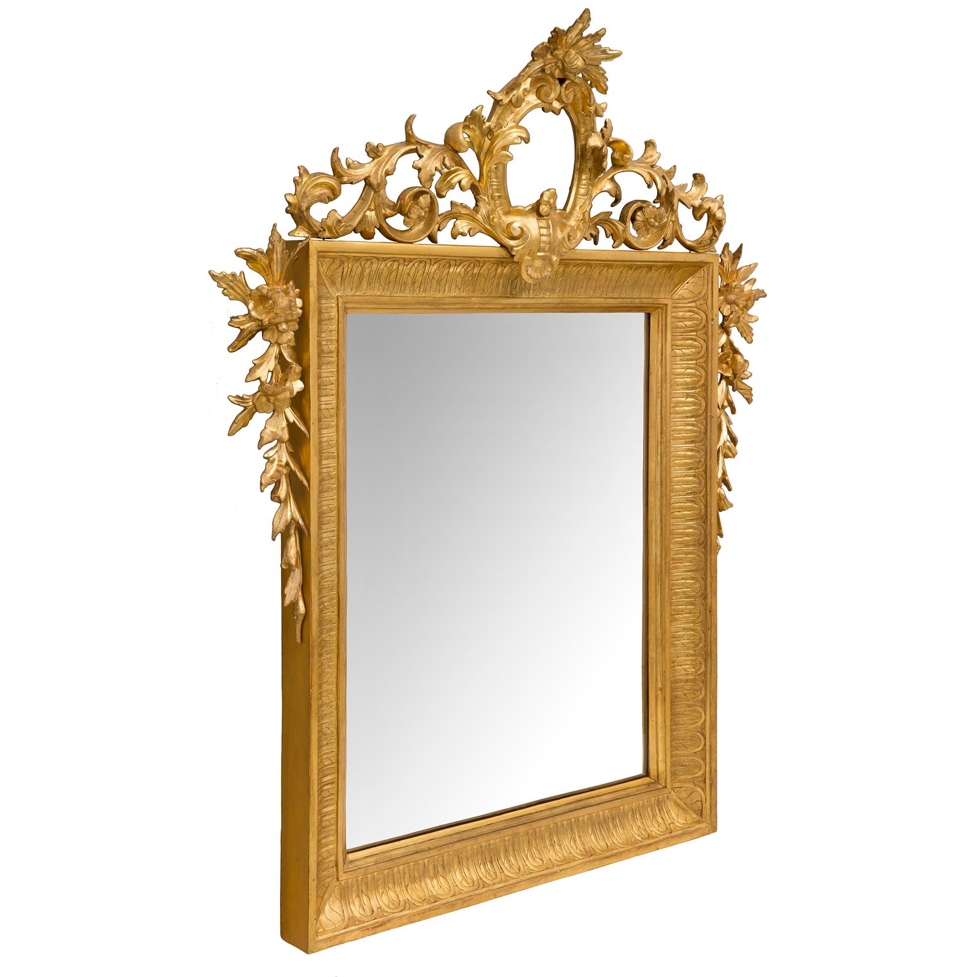 Une superbe paire de miroirs en bois doré de style Louis XVI du 19ème siècle. Chaque miroir conserve sa plaque d'origine encadrée dans un beau cadre en bois doré moucheté avec des motifs feuillus. De chaque côté et au sommet de la couronne, on