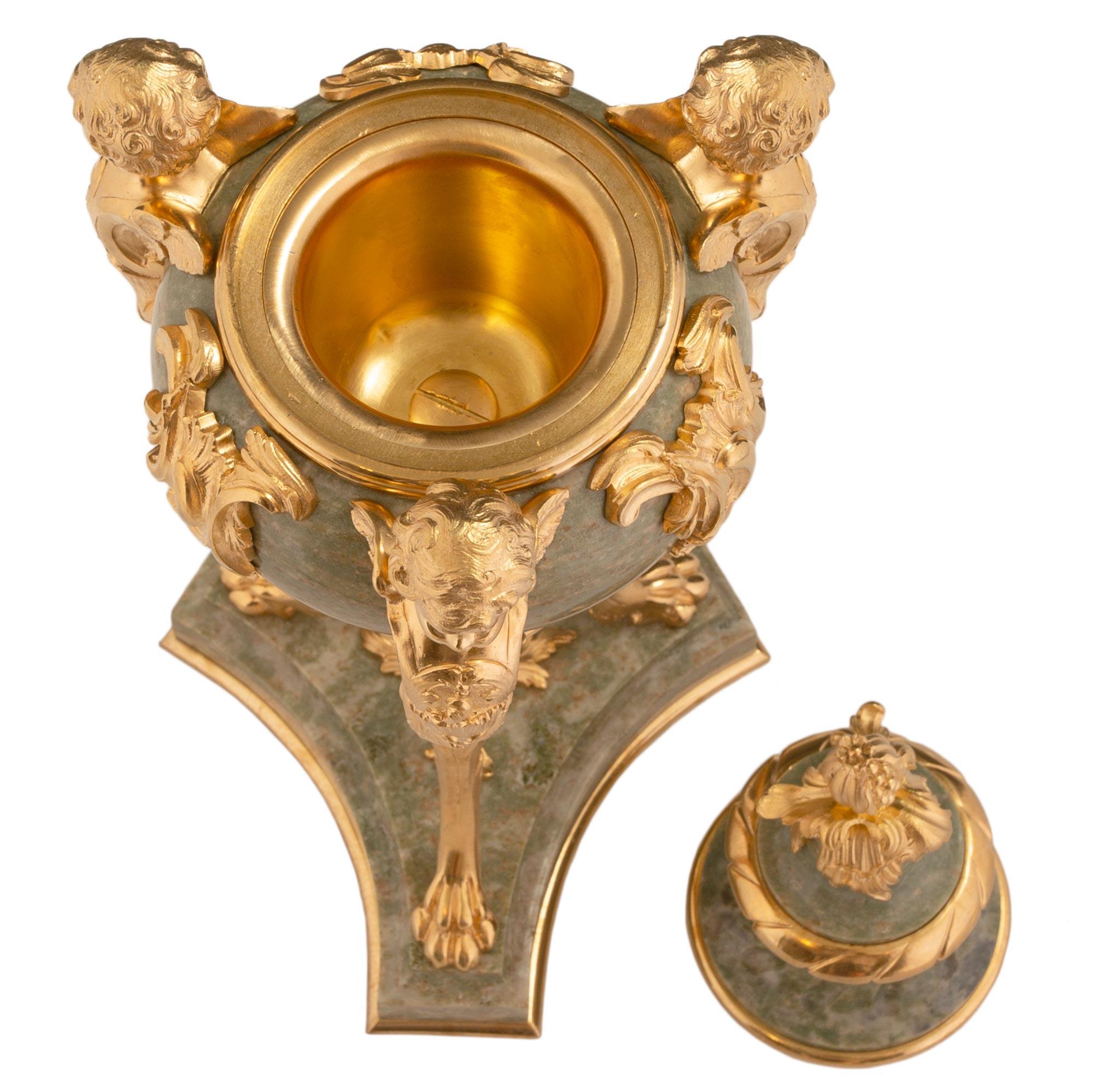 Une belle paire d'urnes à couvercle en marbre vert et bronze doré, de style Louis XVI, datant du 19e siècle. Chaque urne est surélevée par une base triangulaire aux côtés concaves et un fin filet de fond en bronze doré. Les trois supports situés