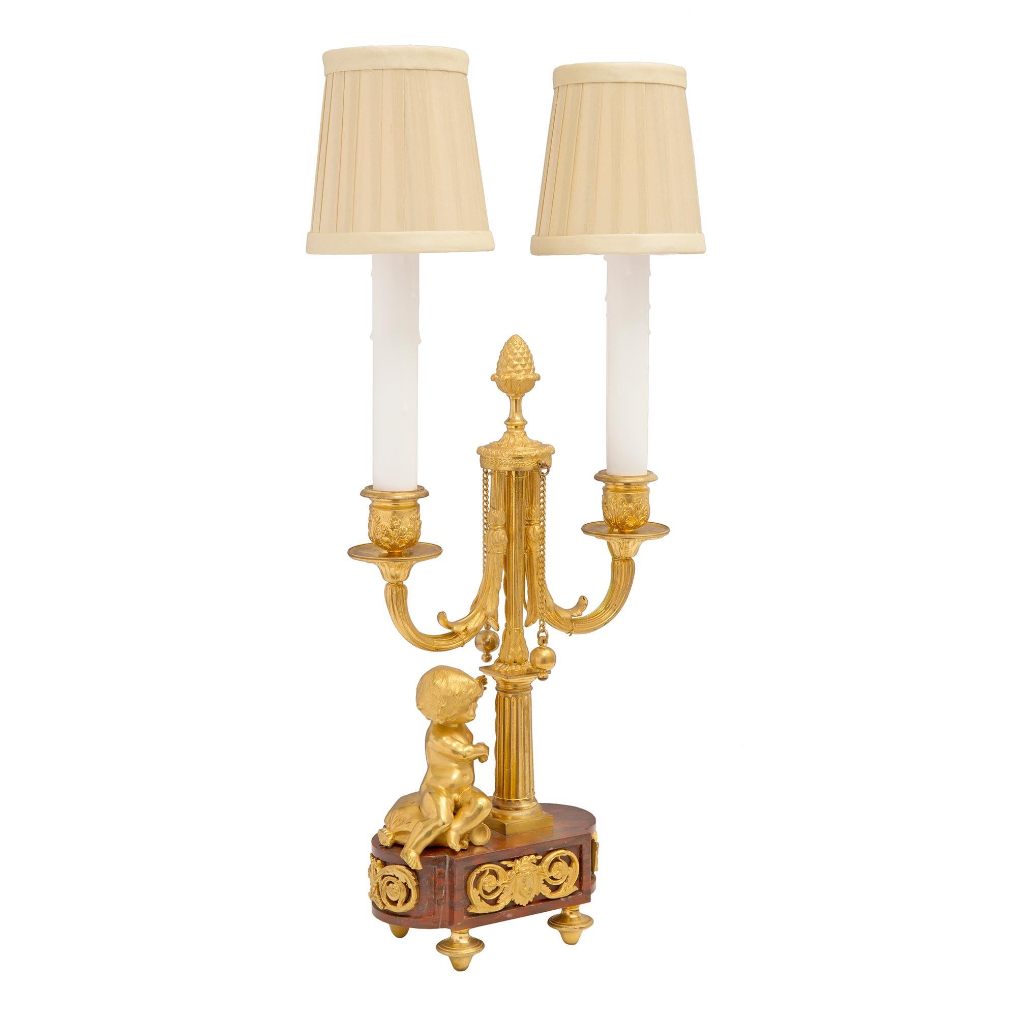 A high quality and most charming true pair of French 19th century Louis XVI st. Rouge Griotte marble and ormolu two arm candelabra lamps. Each lamp is raised by elegant ormolu topie shaped feet below the oval shaped Rouge Griotte marble base, with