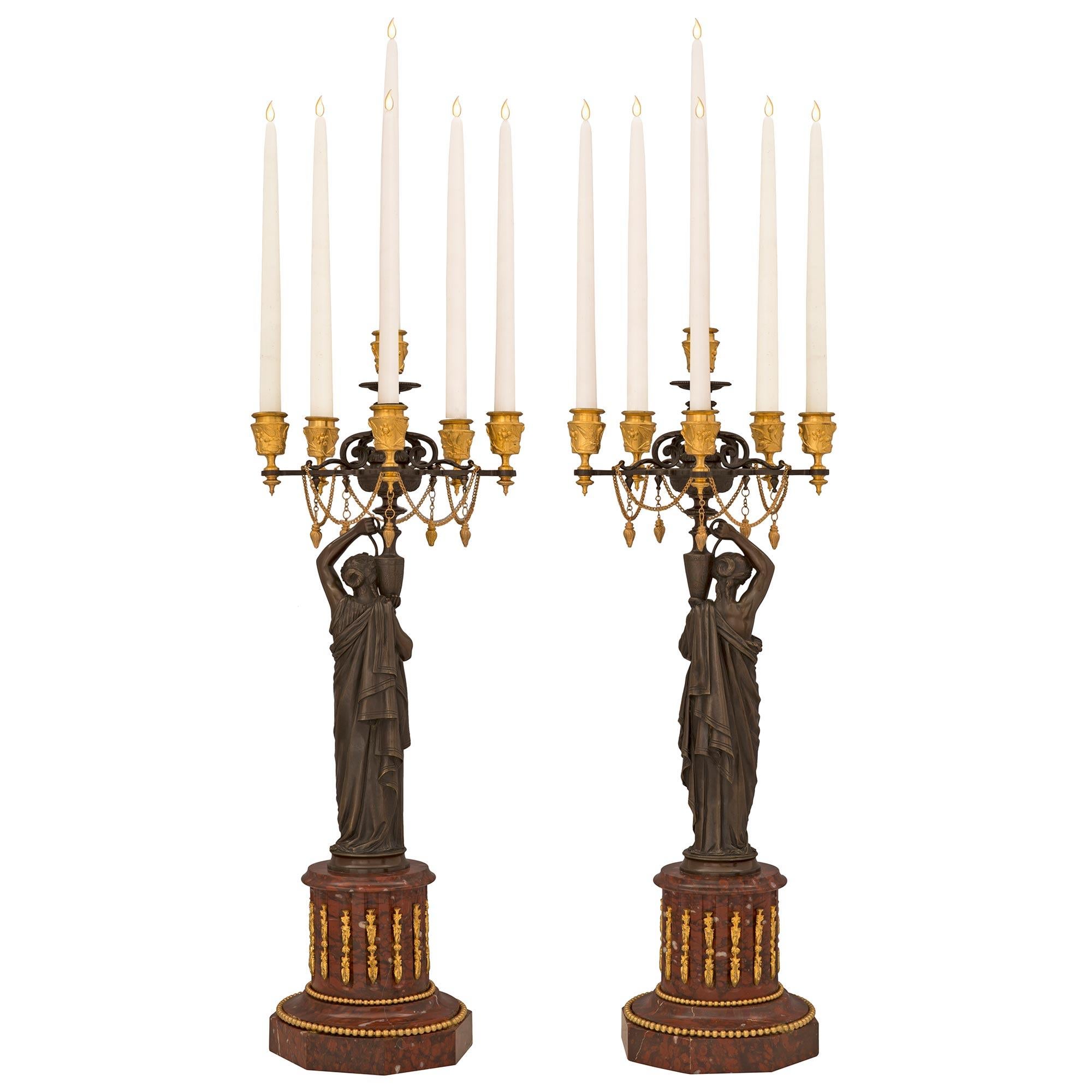 A striking and high quality true pair of French 19th century Louis XVI st. patinated bronze, ormolu, and Rouge Griotte marble candelabras, attributed to H. Ferrat. Each six arm candelabra is raised by an octagonal Rouge Griotte marble base with a