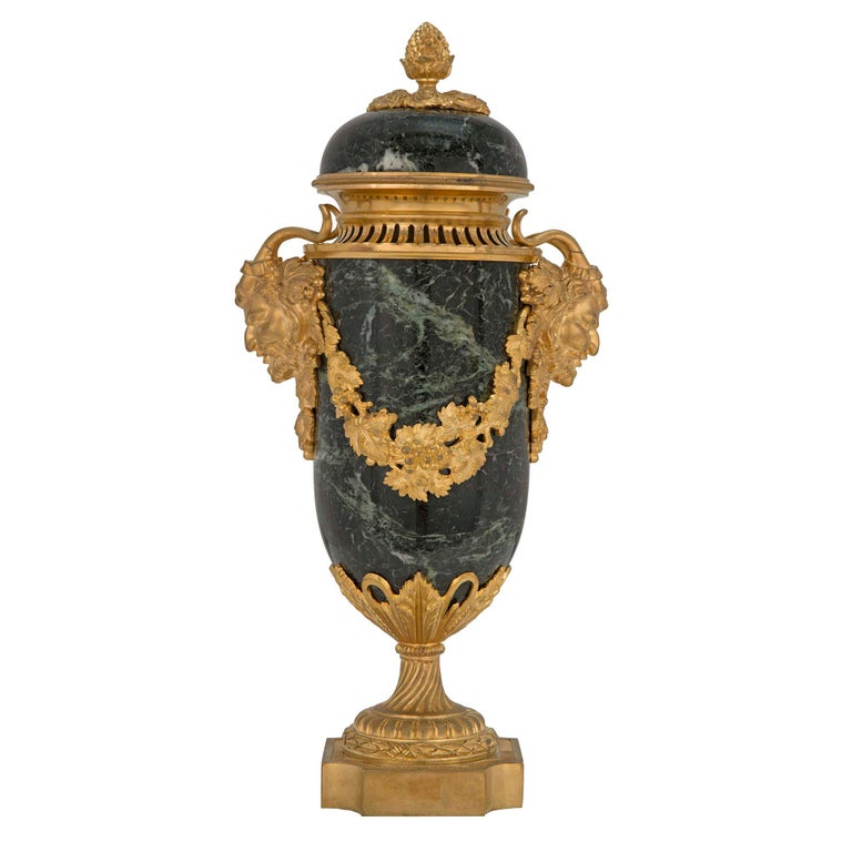 A high quality pair of French 19th century Louis XVI st. Vert Patricia marble and ormolu lidded urns. Each urn is raised by a square ormolu base with concave corners decorated with a tied berried laurel band and a les oves pattern. Above the spiral