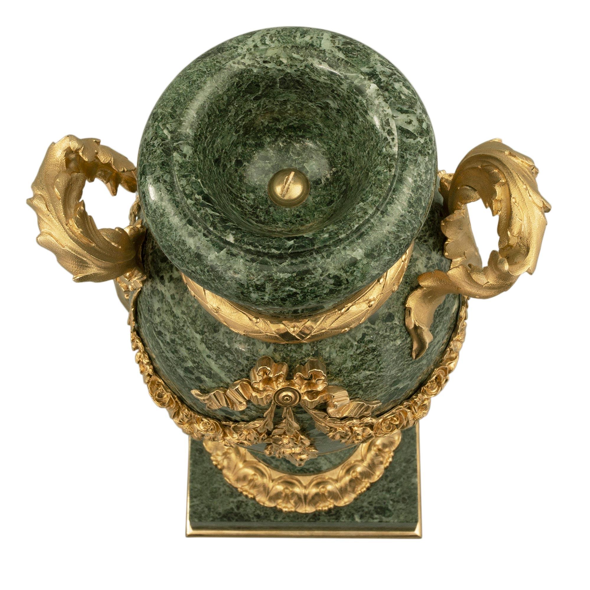 A striking pair of French 19th century Louis XVI st. Vert de Patricia marble and ormolu urns. Each urn is raised by a square marble base with a fine bottom ormolu band. The socle pedestals display finely chased foliate wrap around ormolu bands and