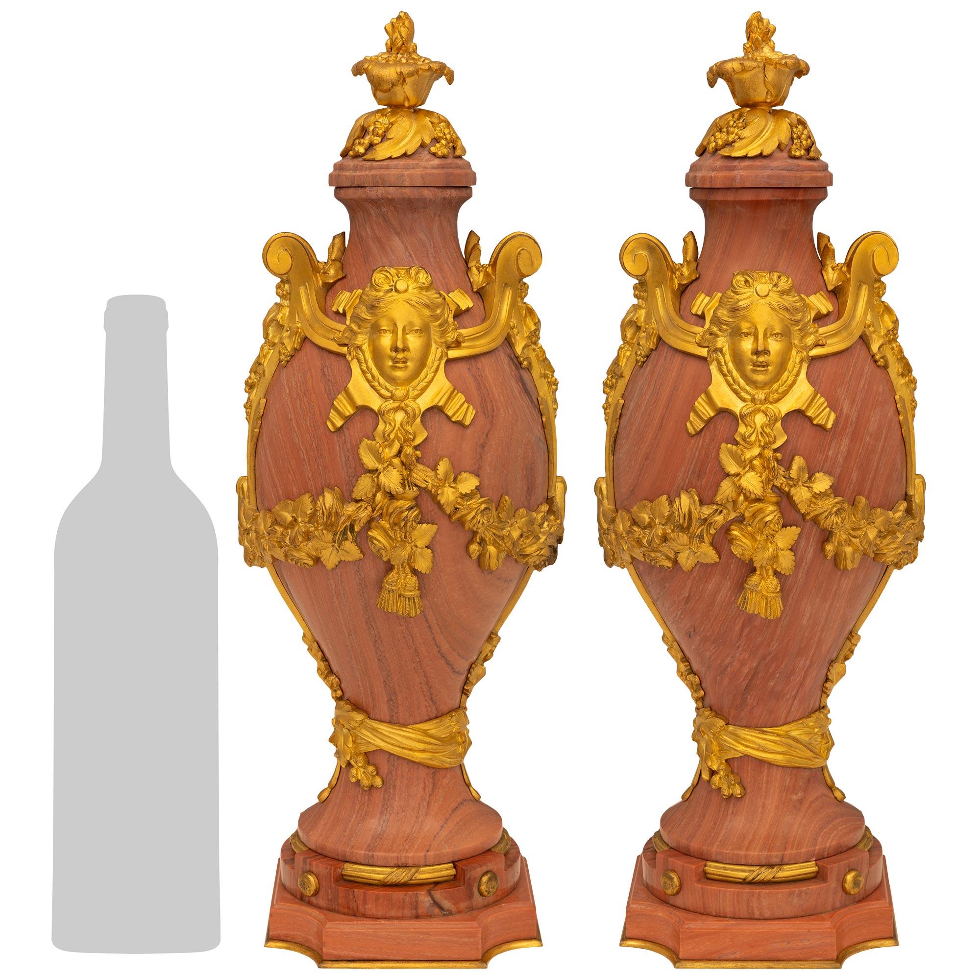 Une impressionnante paire d'urnes en marbre et bronze doré de style Louis XVI du XIXe siècle. Chaque urne de forme unique est surmontée d'une base carrée en marbre aux angles concaves et d'une bande inférieure en bronze doré. Le support circulaire
