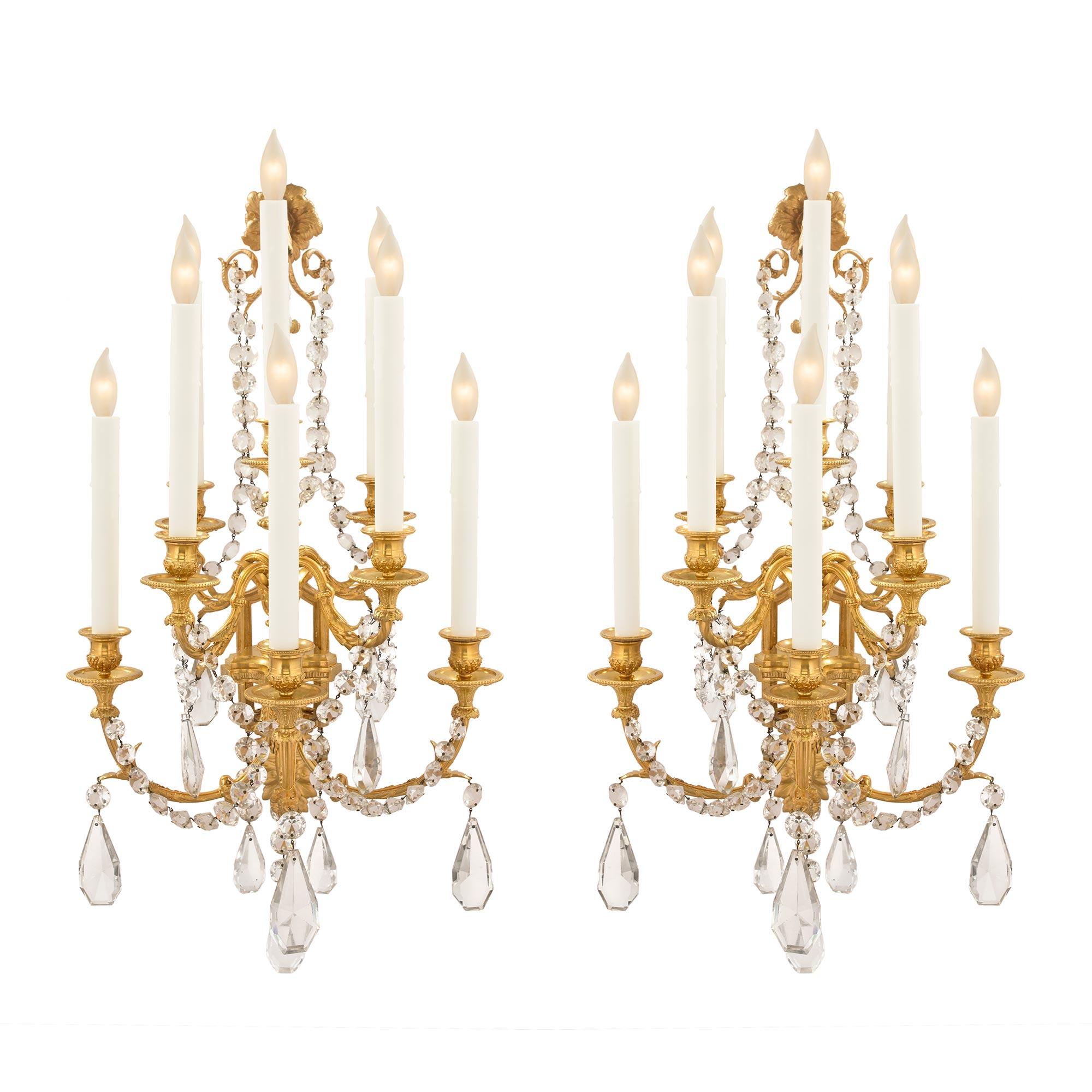 A stunning pair of French 19th century Louis XVI style ormolu and Baccarat crystal eight arm sconces. Each sconce is centered by a beautiful and richly chased foliate back plate with a scrolled wheat sprig. Each elegantly scrolled arm is adorned in