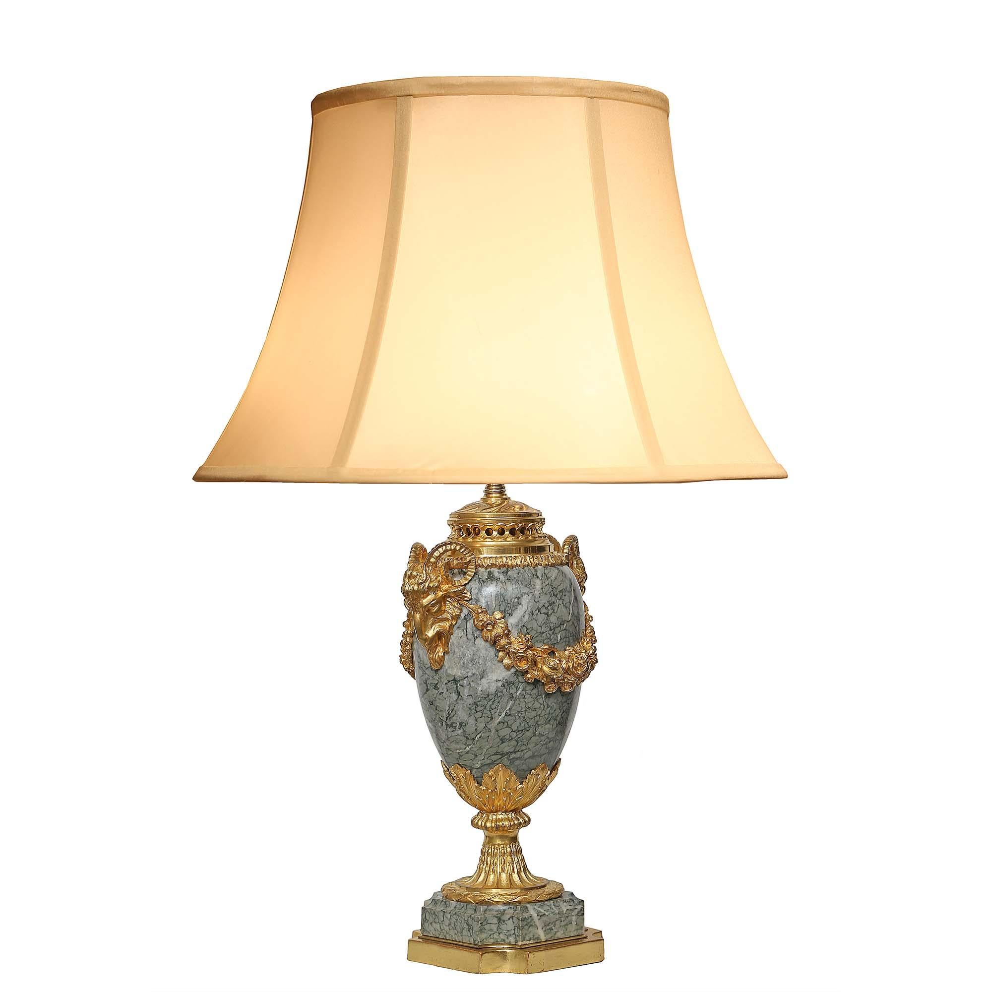 An elegant pair of French 19th century Louis XVI st. ormolu and marble urns mounted into lamps. Each lamp is raised on a square gilt wood and marble base with concave corners. The richly chased satin and burnished finished socle pedestal with a