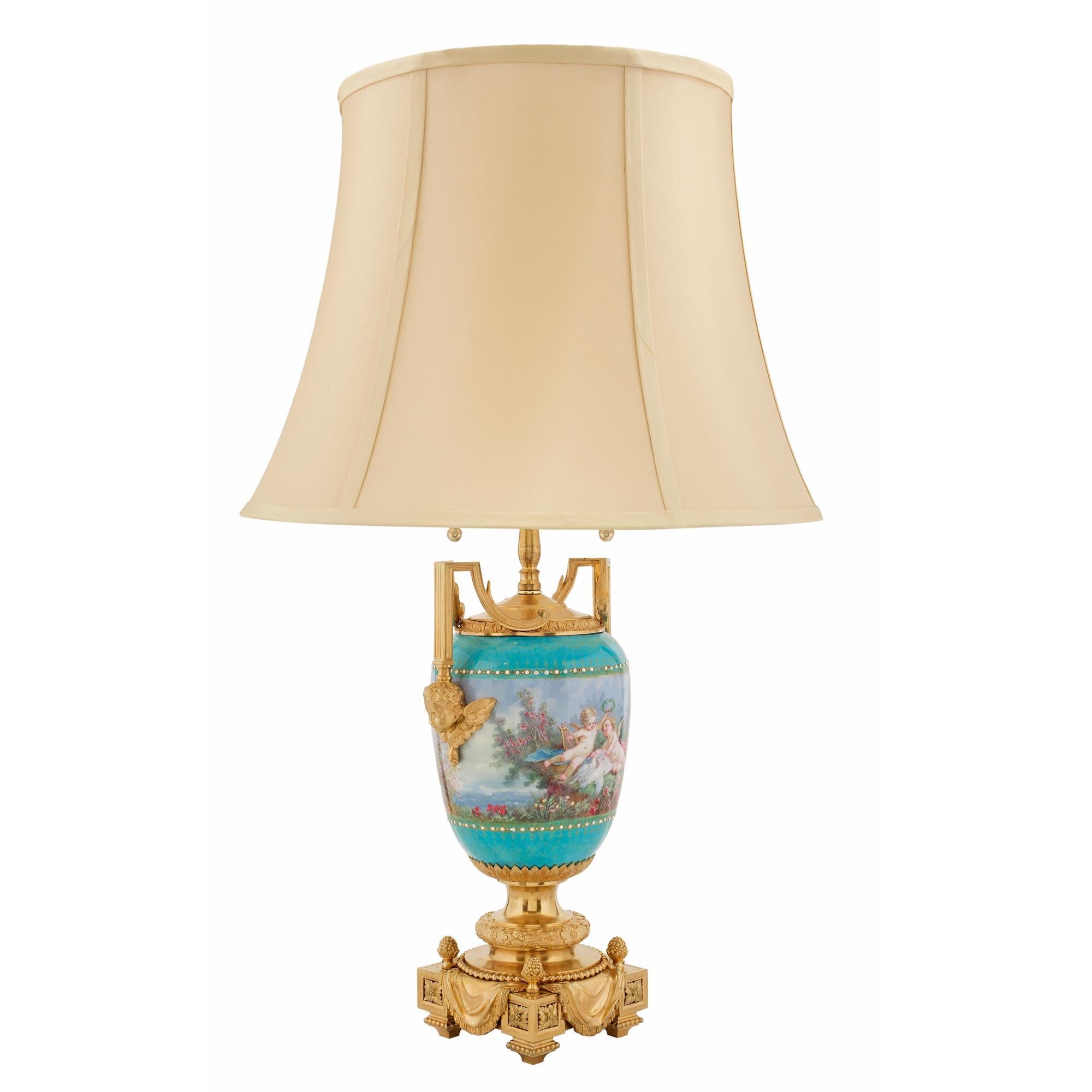 A stunning pair of French 19th century Louis XVI st. ormolu and enameled porcelain lamps hand signed by Picard. Each lamp is raised by a striking and richly detailed ormolu base with block rosettes, a wonderfully executed draped fabric with tassels
