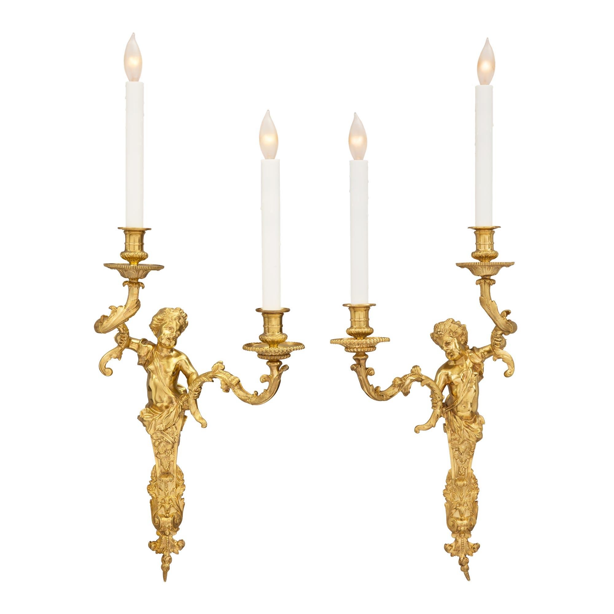 A beautiful and high quality true pair of French 19th century Louis XVI st. ormolu two arm sconces of Bacchus and Ariadne, after a model by Gilles-Marie Oppenordt and attributed to Henry Dasson. Each sconce is centered by a lovely foliate bottom