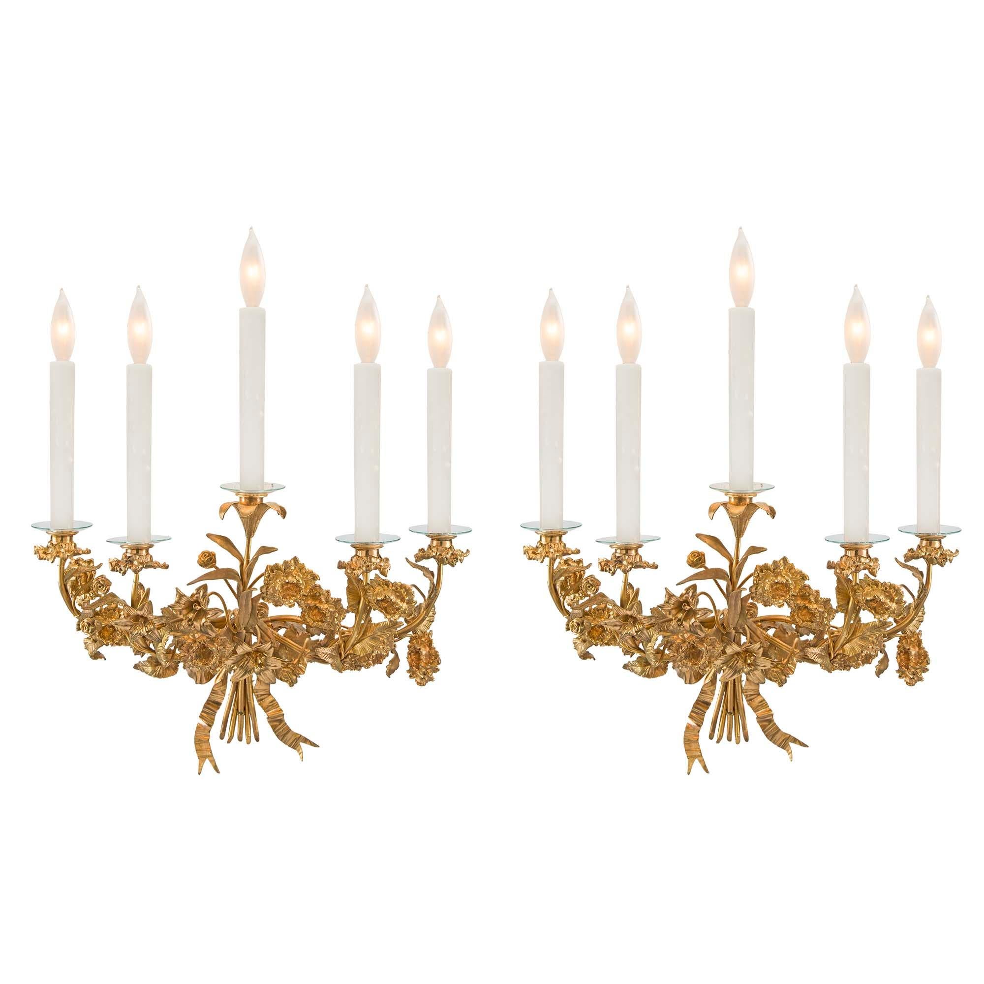 A beautiful and very decorative pair of French 19th century Louis XVI style ormolu sconces. Each five light sconce is in a fanciful shape of a bouquet of flowers. Centered by stems tied by a bow. The arms are adorned with finely chased flower