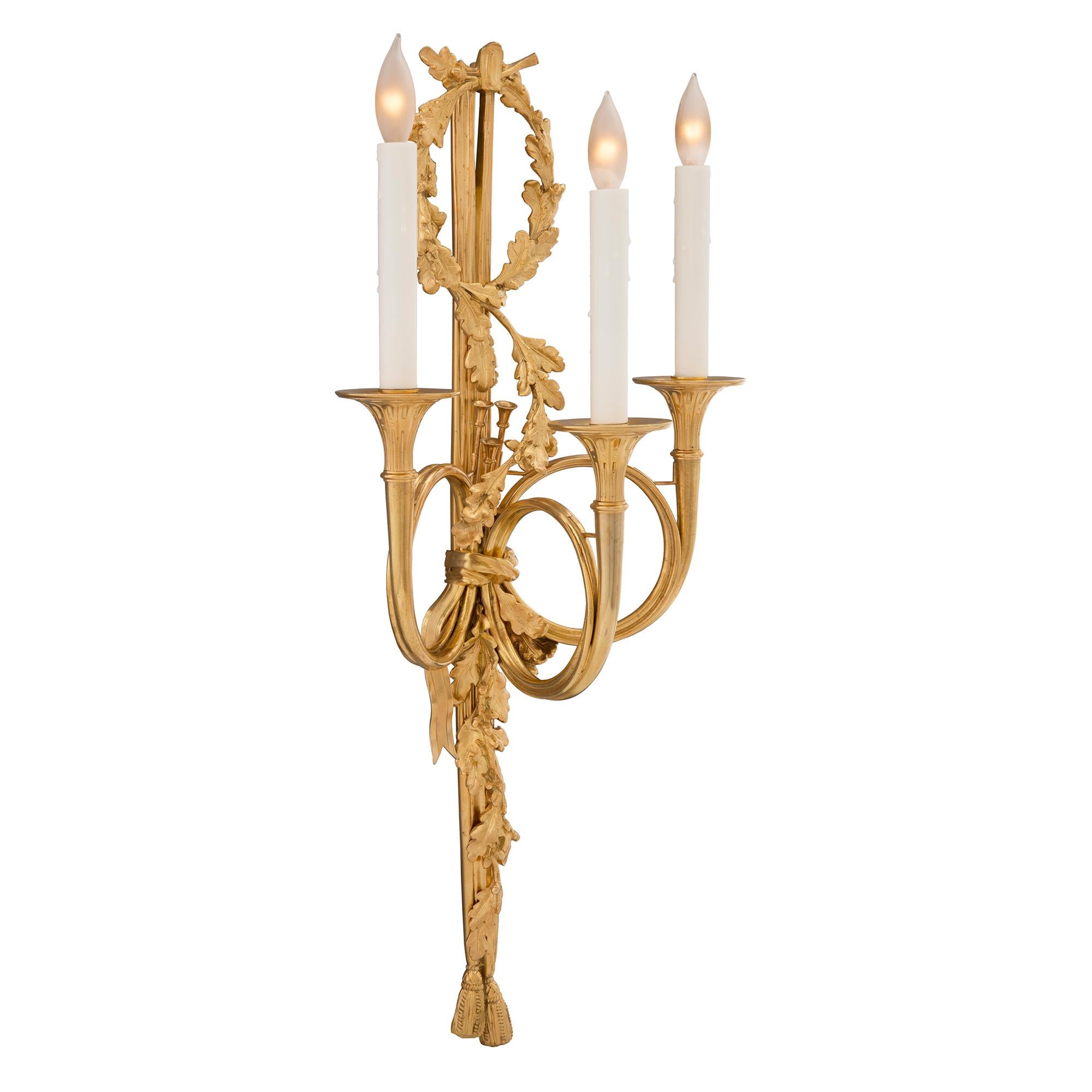 Paire d'appliques à trois bras de lumière en bronze doré, d'après un modèle de Claude Galle, datant du XIXe siècle. Chaque applique est centrée par d'élégants glands inférieurs avec de magnifiques glands et feuilles de chêne richement ciselés qui