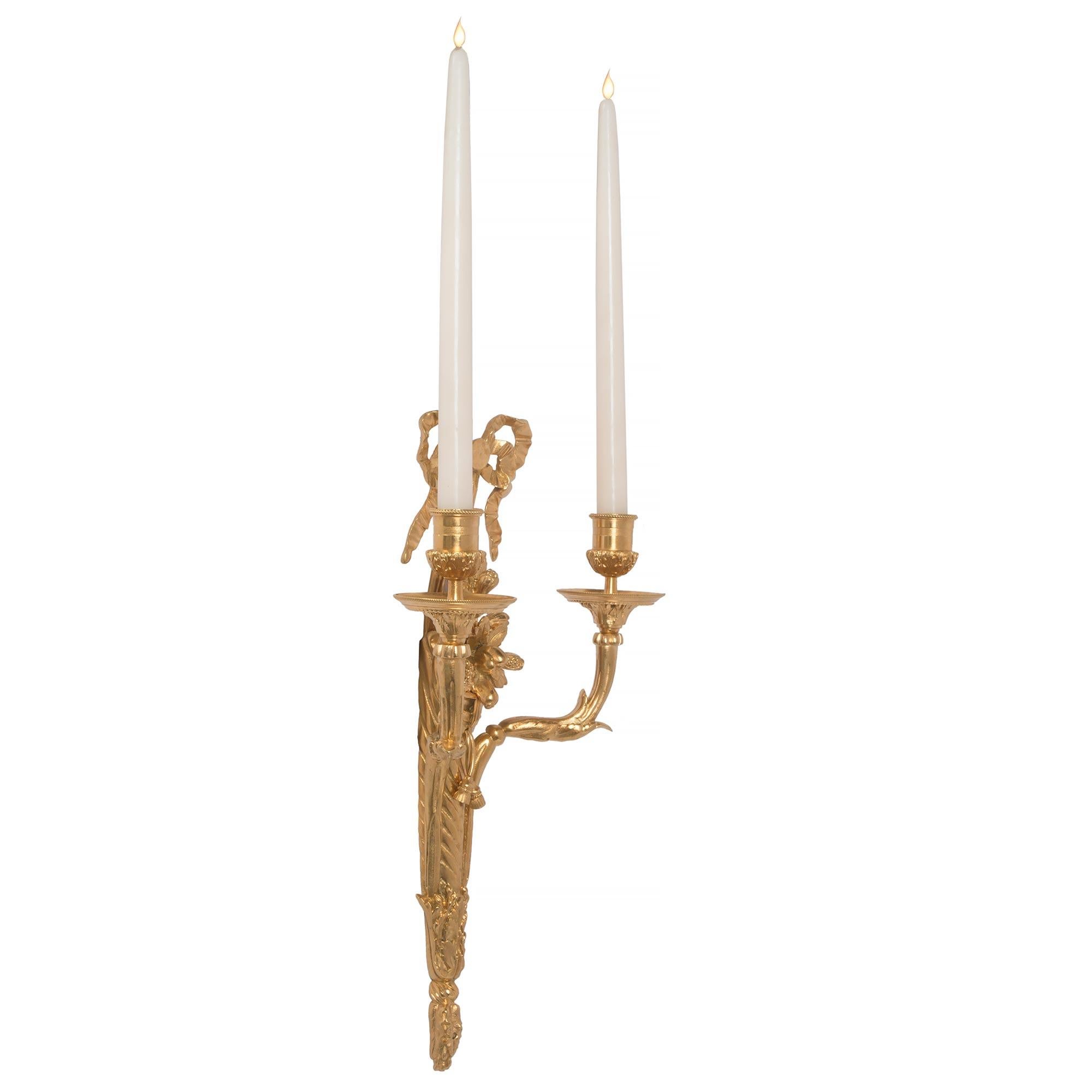 An extremely elegant pair of French 19th century Louis XVI St. ormolu two arm sconces. Each sconce is centered by a beautiful foliate finial below the twisted central support. Each S-scrolled arm is decorated with large acanthus leaves and Fine