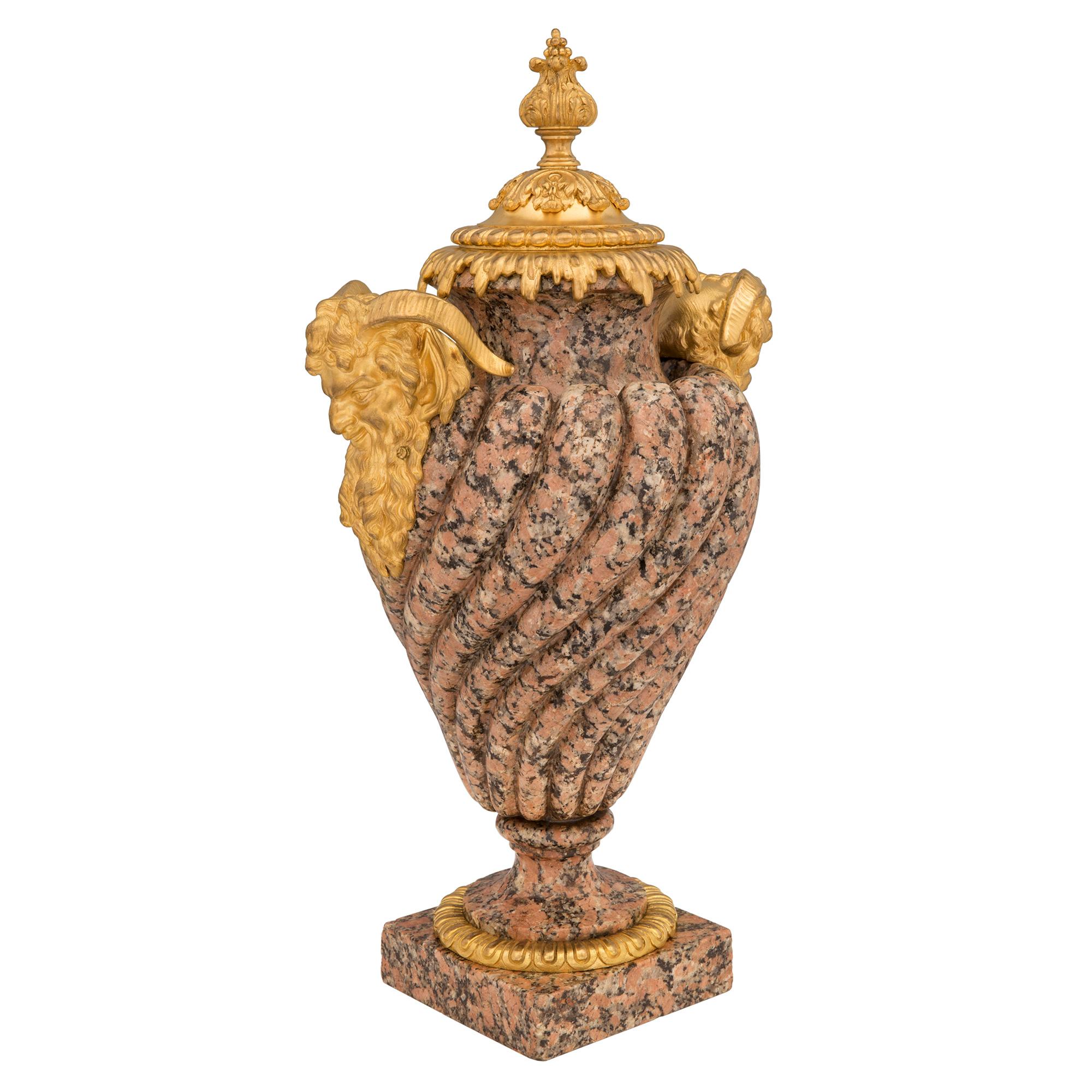 An impressive and high quality pair of French 19th century Louis XVI st. pink granite and ormolu urns. Each urn is raised by a square base decorated with a fine wrap around ormolu band. Above the socle pedestals are the stunning and wonderfully