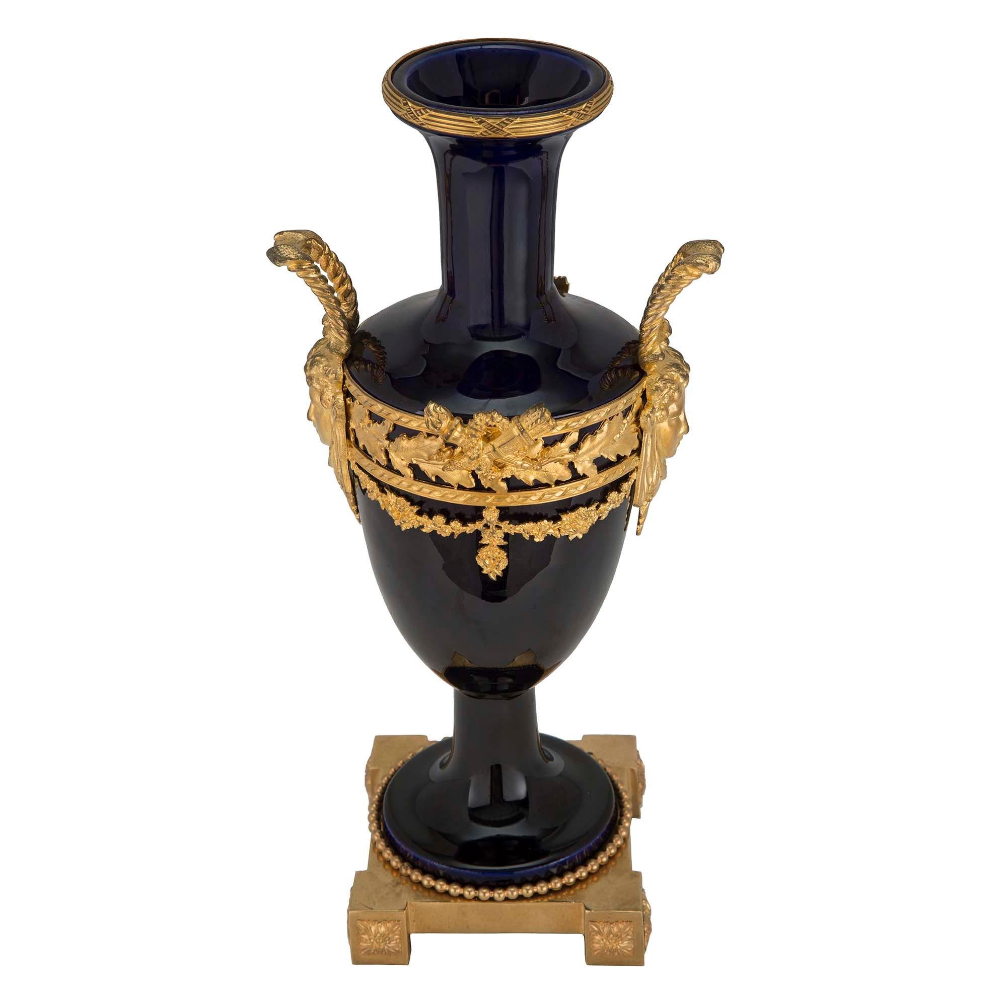 Un'elegantissima coppia di vasi in porcellana blu cobalto e ormolo del XIX secolo, forse di Sèvres. Ogni vaso è sollevato da una base quadrata in ormolu con riserve di rosette a blocco in ogni angolo e una fascia decorativa in ormolu con perline. Il