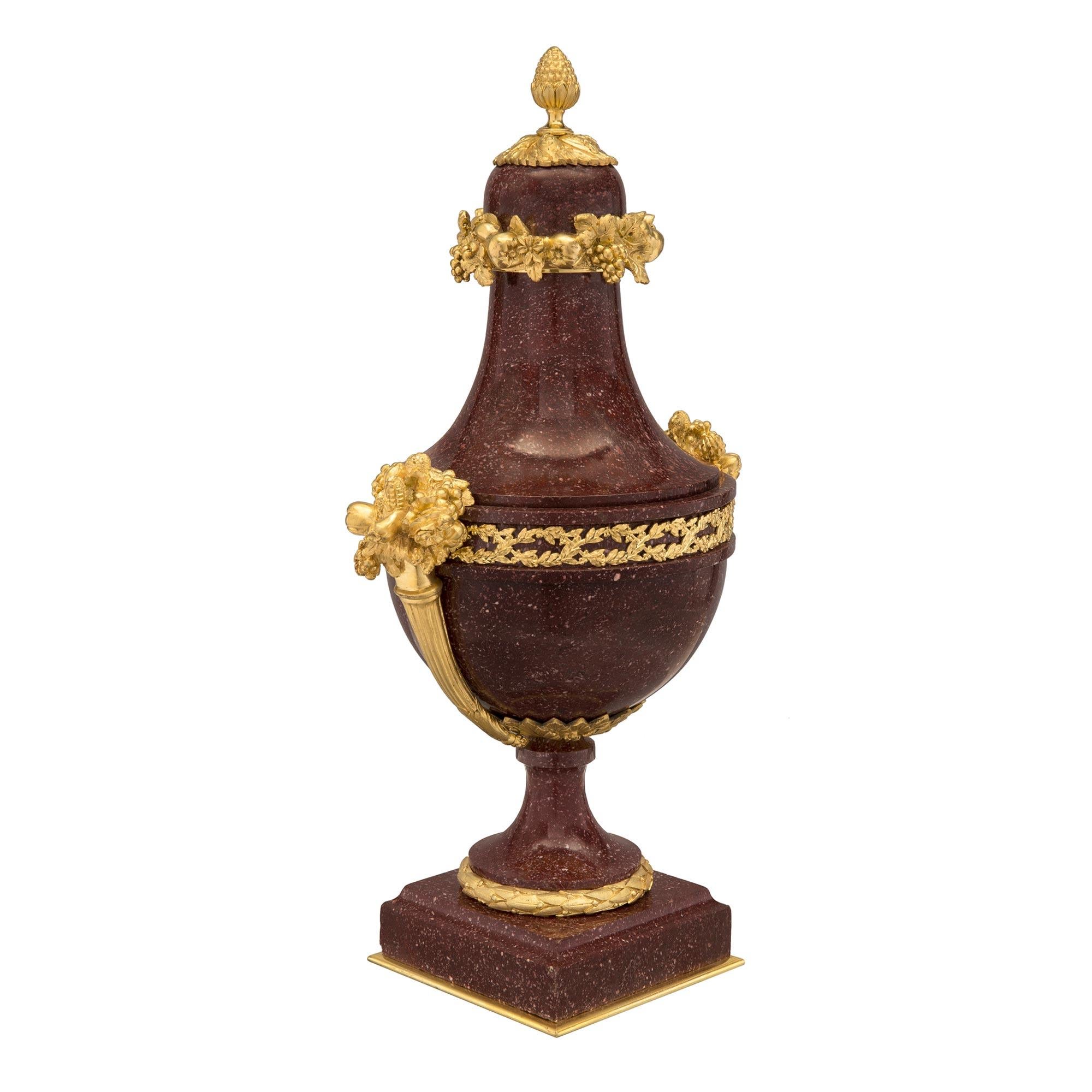 A sensational and high quality pair of French mid 19th century Louis XVI st. Porphyry and fire gilded ormolu lidded urns. The pair are raised by a square ormolu plate below the mottled square marble base. The socles are surrounded by a beaded laurel
