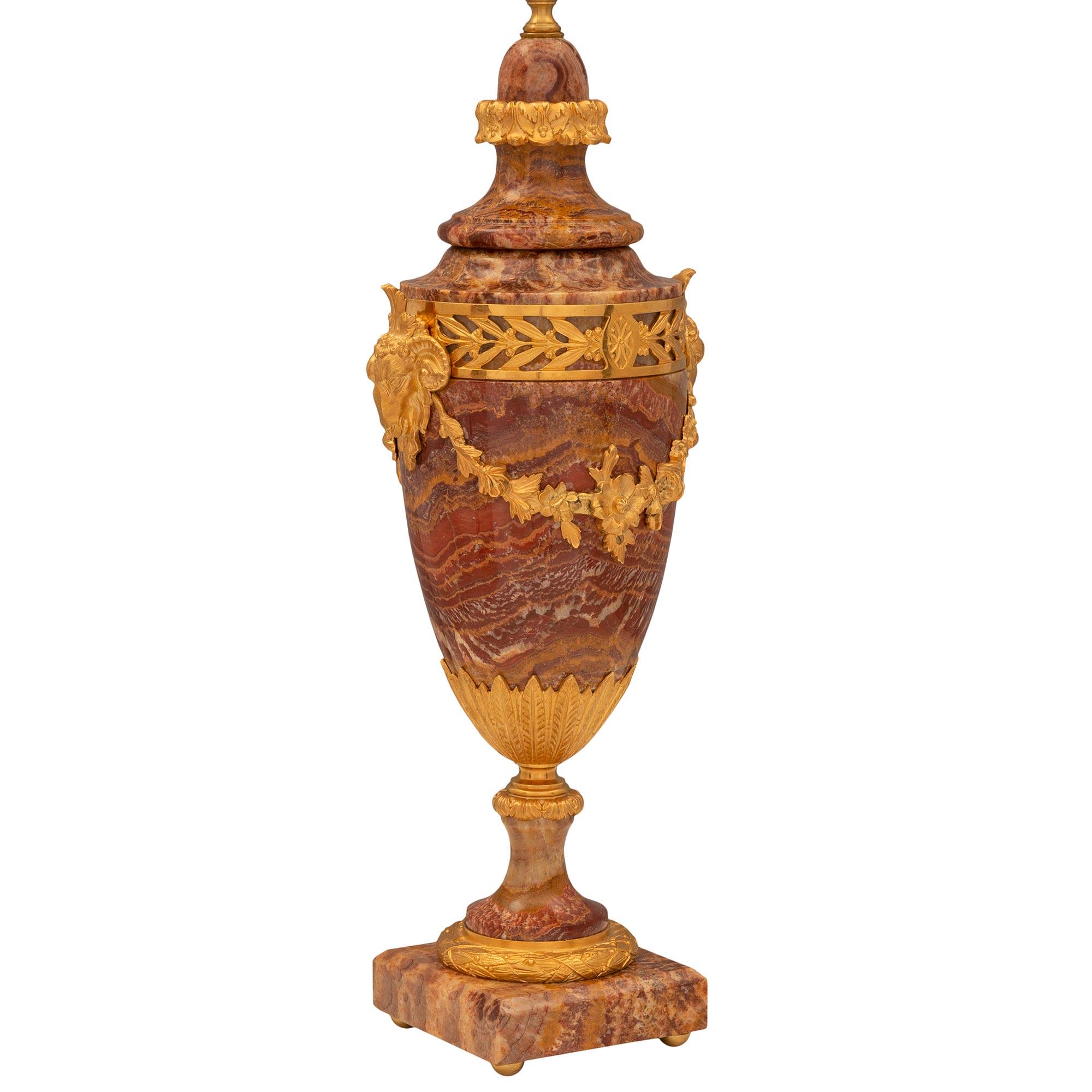 An exceptional and most decorative pair of French 19th century Louis XVI st. red Vulcano onyx and ormolu lamps. Each lamp is raised by a square base with fine ormolu ball feet and a beautiful wrap around tied berried laurel ormolu band at the