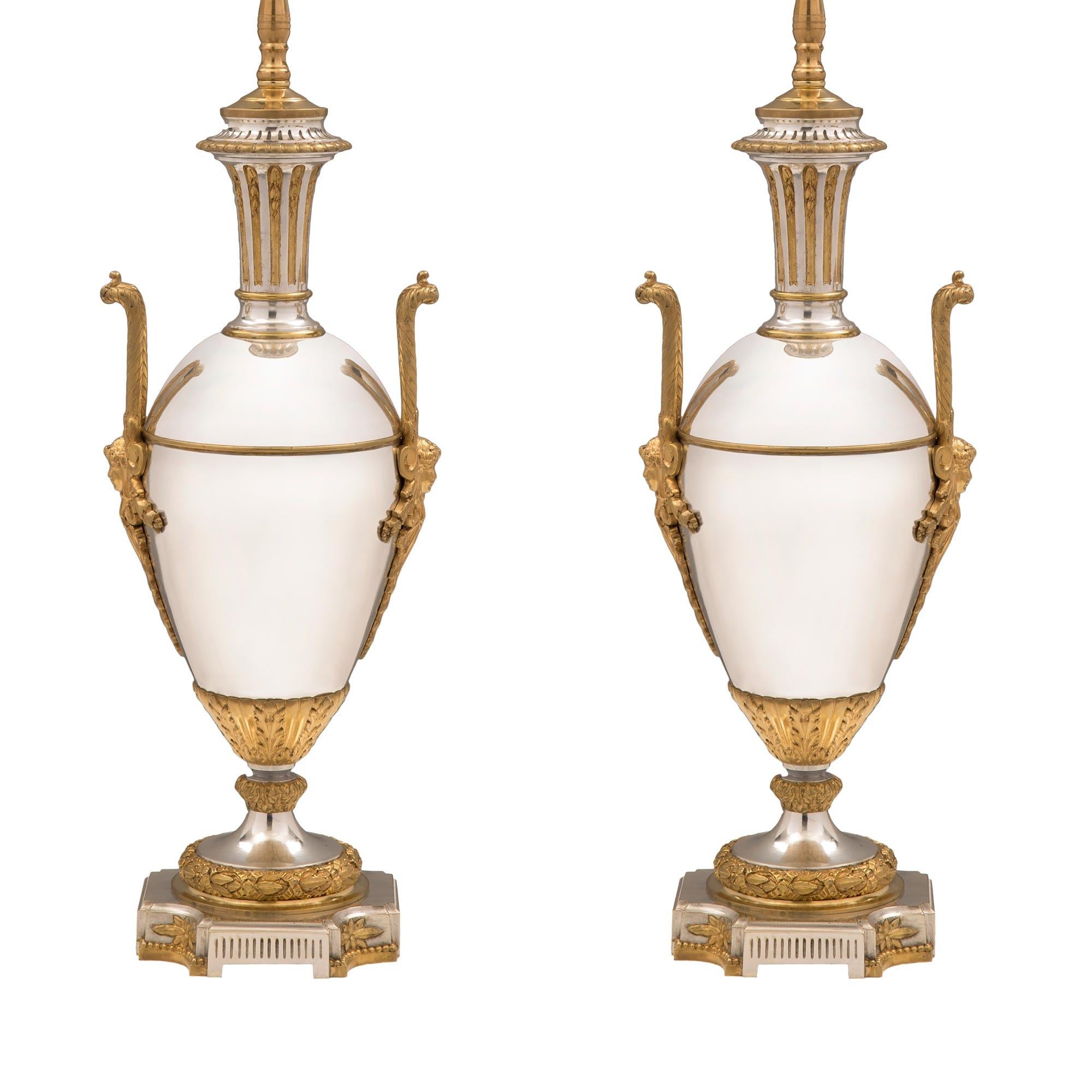 A striking and most elegant pair of French 19th century Louis XVI style silvered bronze and ormolu lamps. Each lamp is raised by a beautiful square base with concave sides and a fine fluted design with lovely floral rosettes. The socle pedestals
