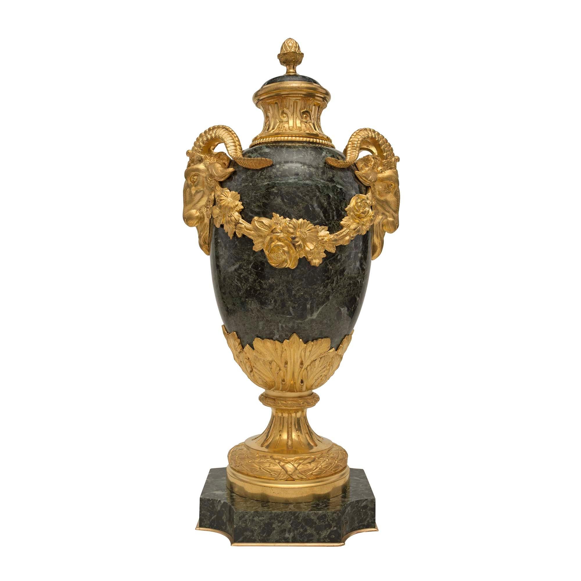 A most elegant pair of French 19th century Louis XVI st. Vert Antique lidded marble urns. Each urn is raised by a square base with concave corner and a decorative bottom ormolu fillet. The fluted socle pedestal is decorated with a tied berried