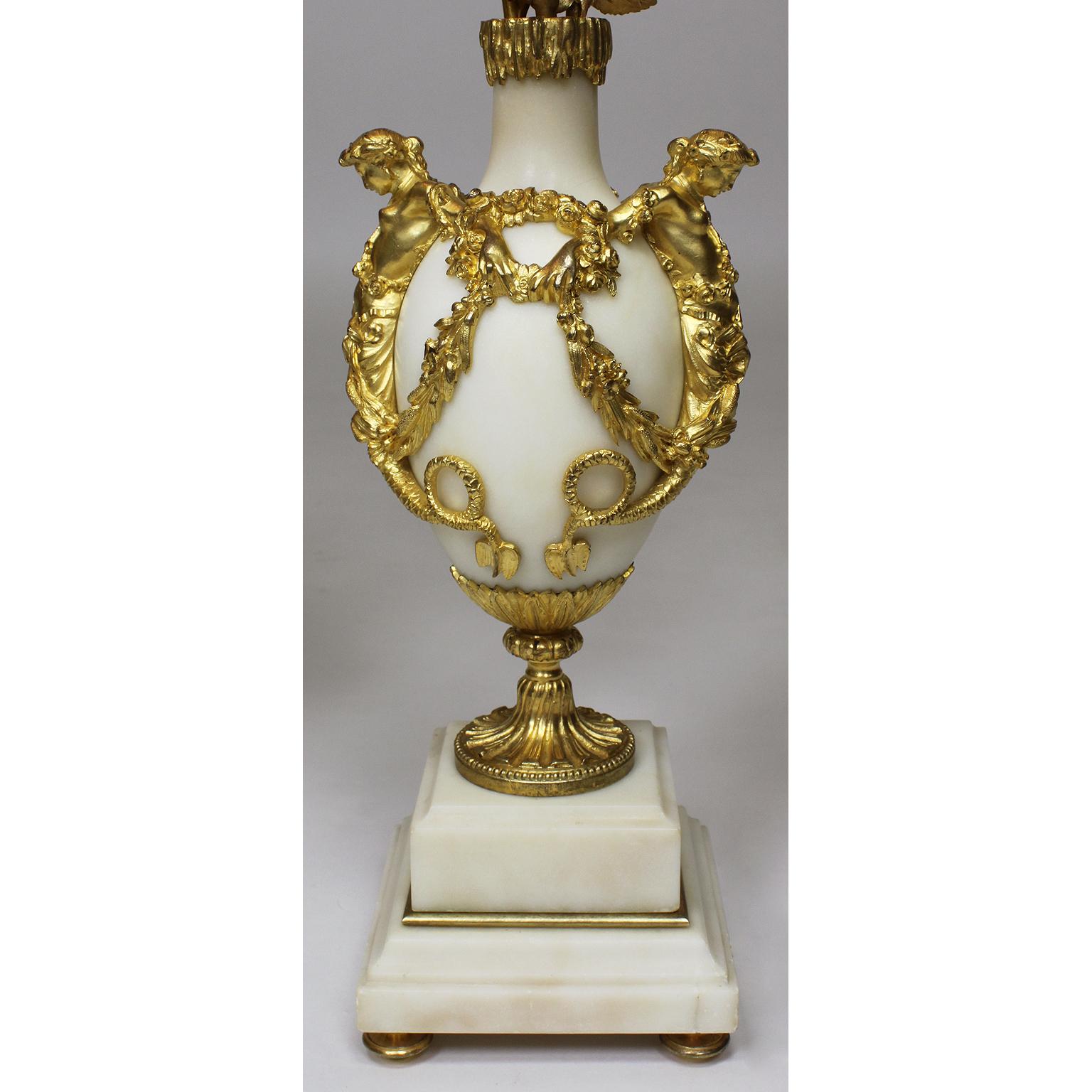 Une belle paire de candélabres de table à trois têtes en marbre et bronze doré du XIXe siècle. Le corps ovoïde en marbre blanc surmonté d'une paire de sirènes se tenant la main avec des couronnes de fleurs, sous un col en forme de glaçon, et d'un