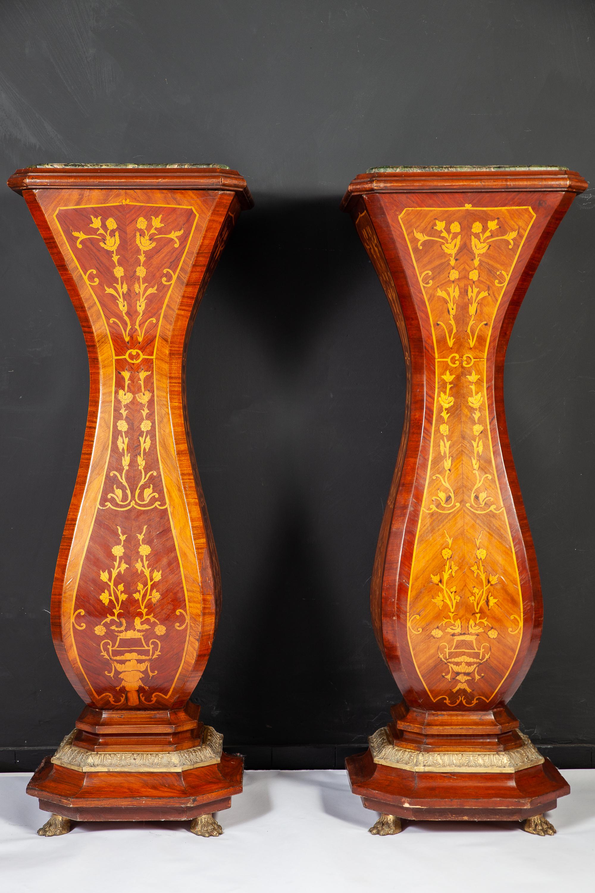 This elegant pair of French 19th century marquetry inlaid pedestals with a green marble top , base with finely carved giltwood decoration terminating with a giltwood lion feet.