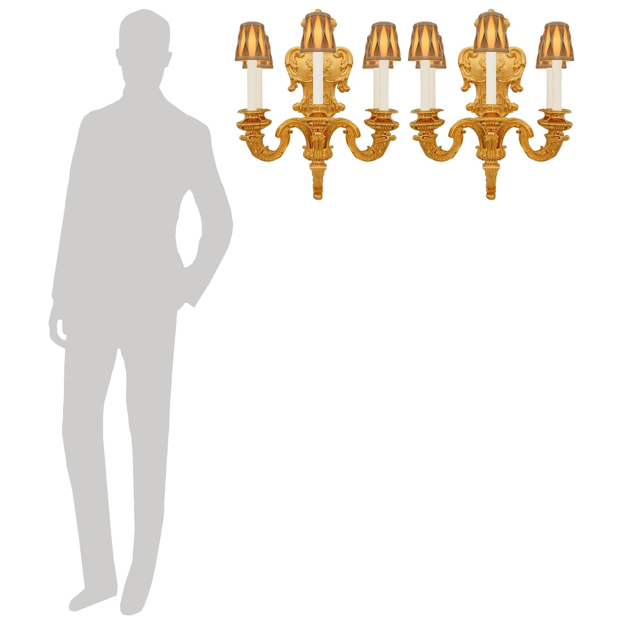 Impresionante y monumental pareja de apliques franceses de Ormolu del siglo XIX, época de Napoleón III y Luis XIV. Este excepcional par de apliques está centrado por una urna ormolu con adornos que se asienta sobre un soporte central. Los cinco