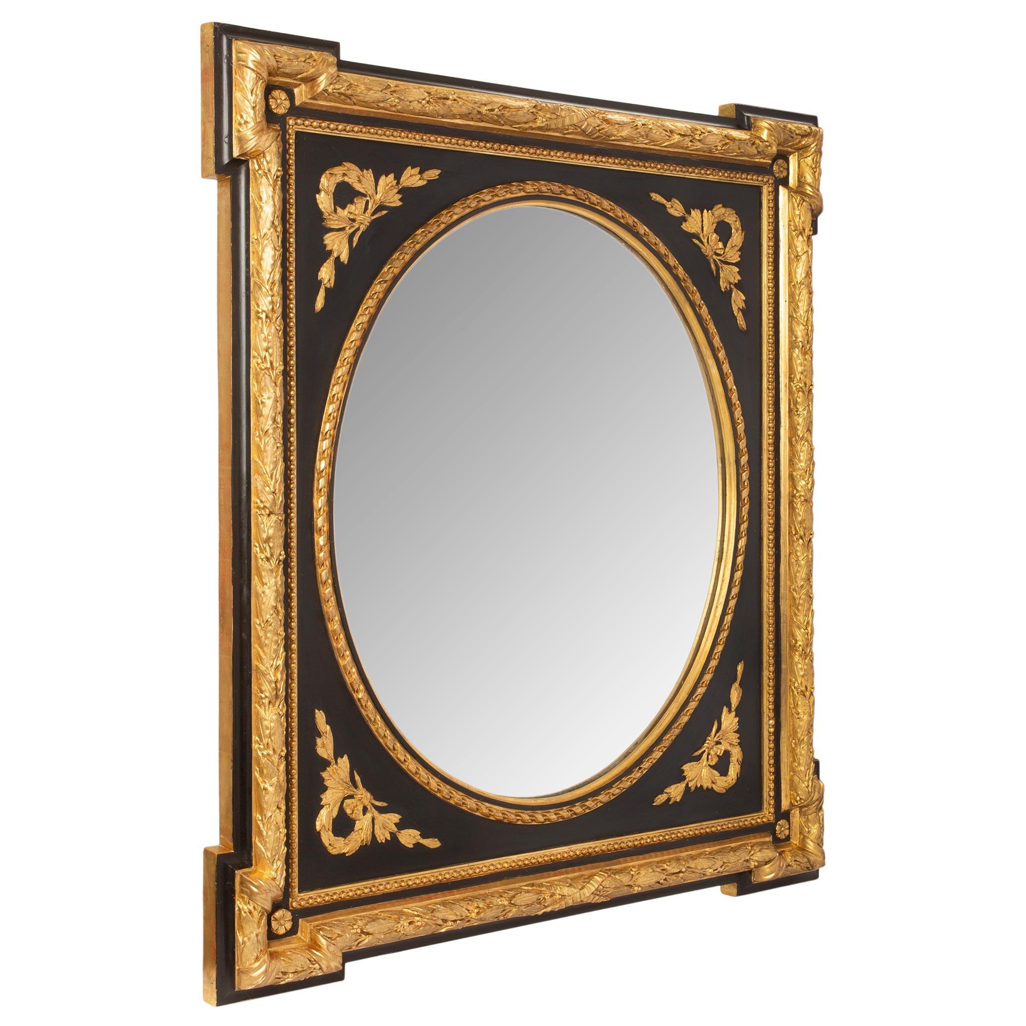 A very attractive pair of French 19th century Napoleon III period Louis XVI st. polychrome and gilt mirrors. The outer edge of the frame has bold and richly detailed berried laurel bands with an X ribbon design at two ends and protruding corners.