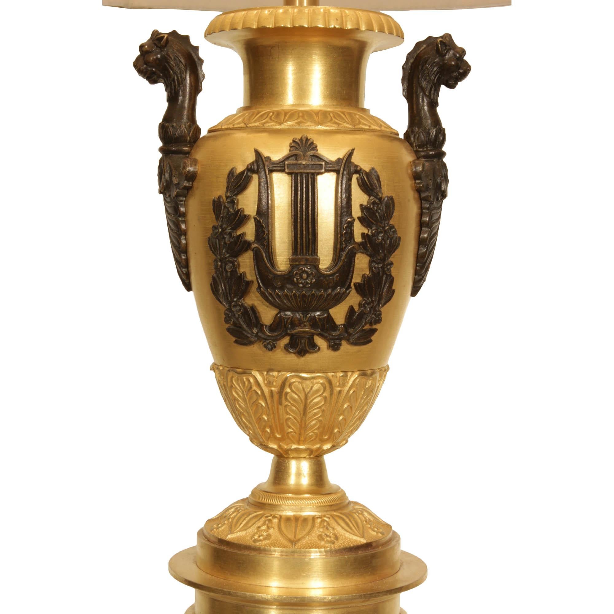 Une merveilleuse paire de lampes néo-cassiques françaises du 19ème siècle en bronze doré et patiné. Chaque lampe repose sur une base carrée en bronze doré et une colonne en bronze patiné. Les éléments en forme d'urne en bronze doré sont ornés de