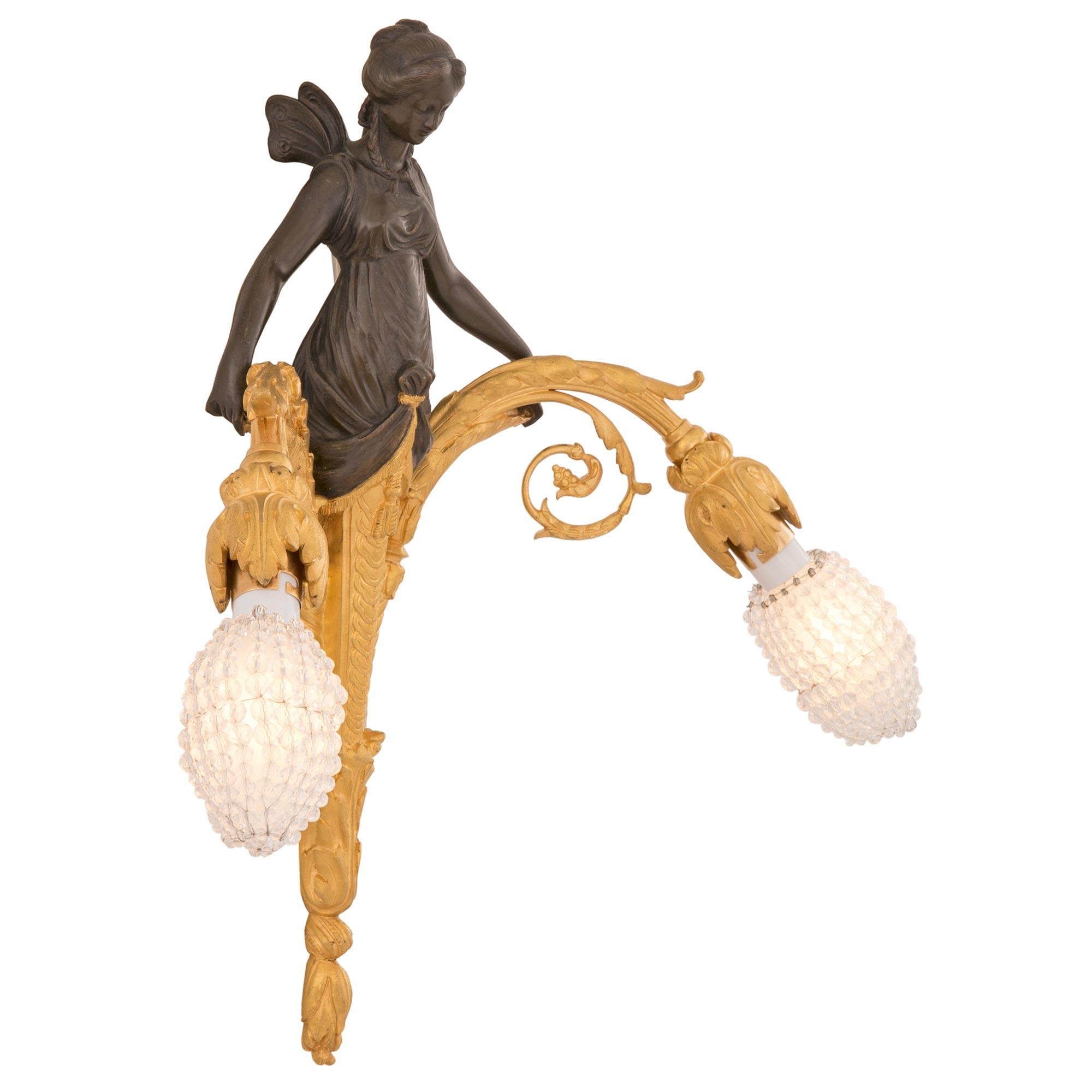 A striking and most unique pair of French 19th century Neo-Classical st. patinated bronze and ormolu sconces. Each two arm sconce is centered by a most elegant tapered central support with a lovely bottom foliate acorn finial and fine overlapping