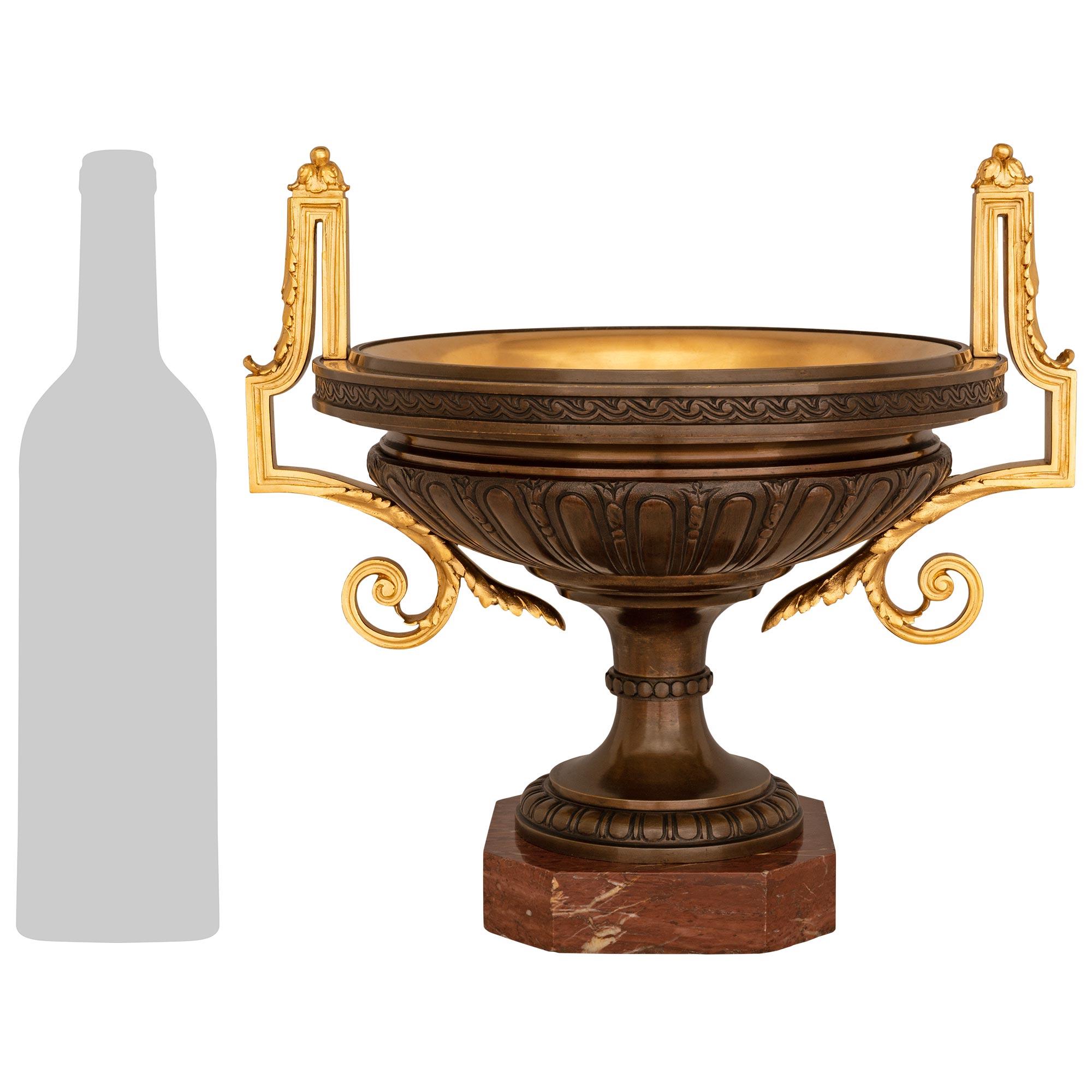 A stunning and most decorative pair of French 19th century Neo-Classical st. Patinated Bronze, Ormolu, and Rouge Griotte marble urns. Each impressive urn is raised by an octagonal Rouge Griotte marble base. The patinated Bronze socle above is