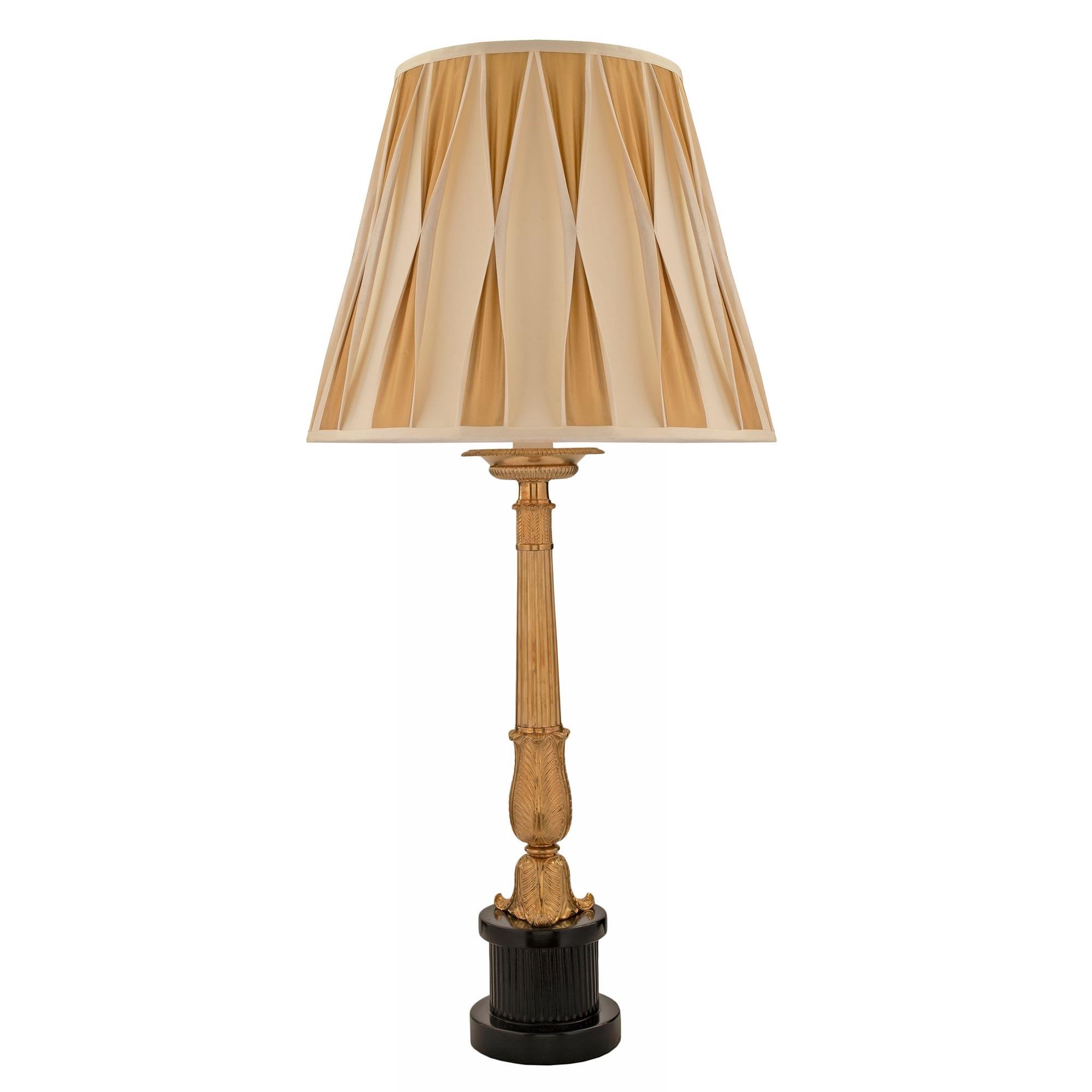 Paire de lampes néo-classiques françaises du 19ème siècle en bois fruitier ébonisé et bronze doré. Chaque lampe est surélevée par une base circulaire très décorative en bois fruitier ébénisé, avec un joli motif cannelé. La colonne en bronze doré