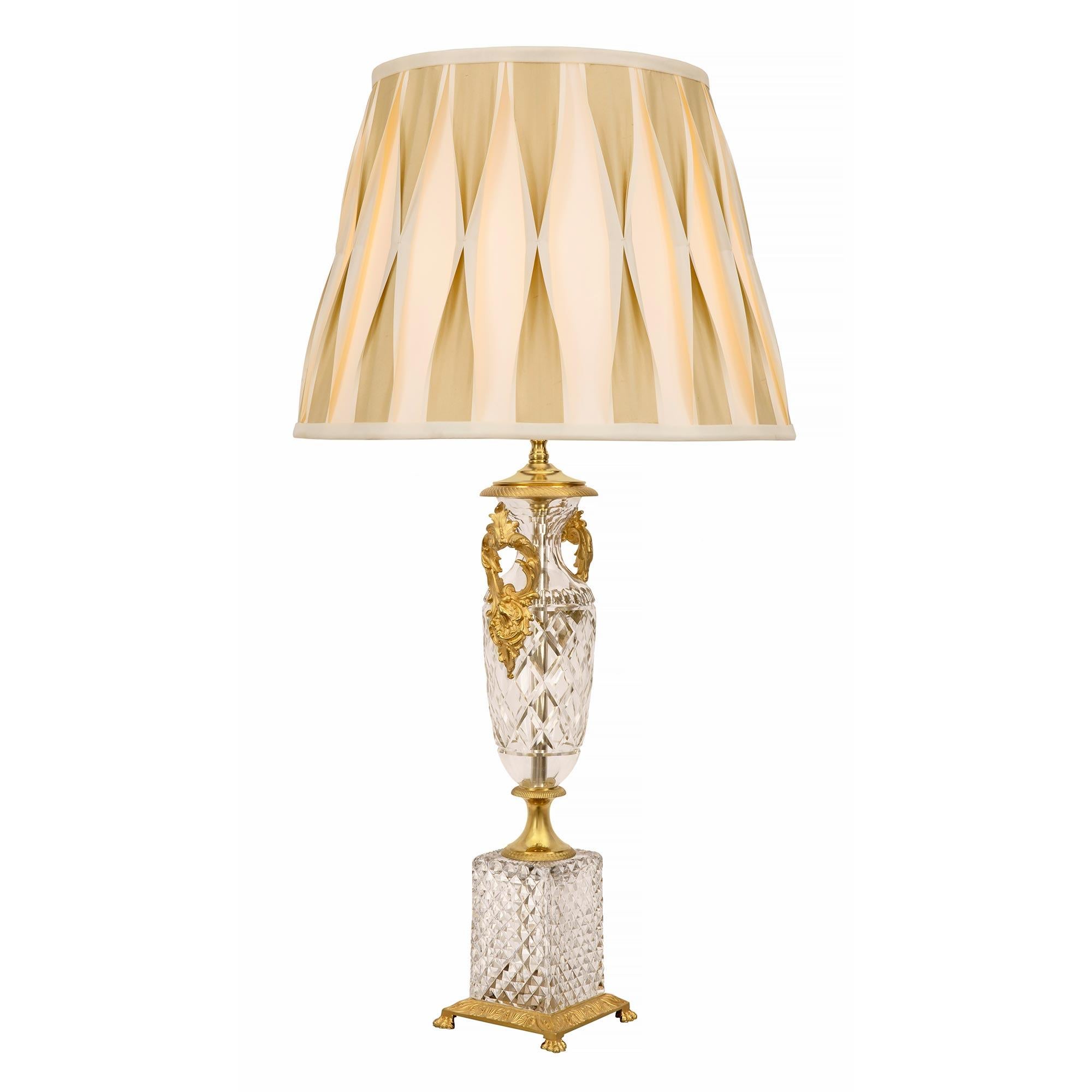 A most elegant pair of French 19th century Neo-Classical st. ormolu and Baccarat crystal lamps. Each lamp is raised by a beautiful square cut crystal base with a beautiful wrap around bottom ormolu band with handsome paw feet. Above the socle
