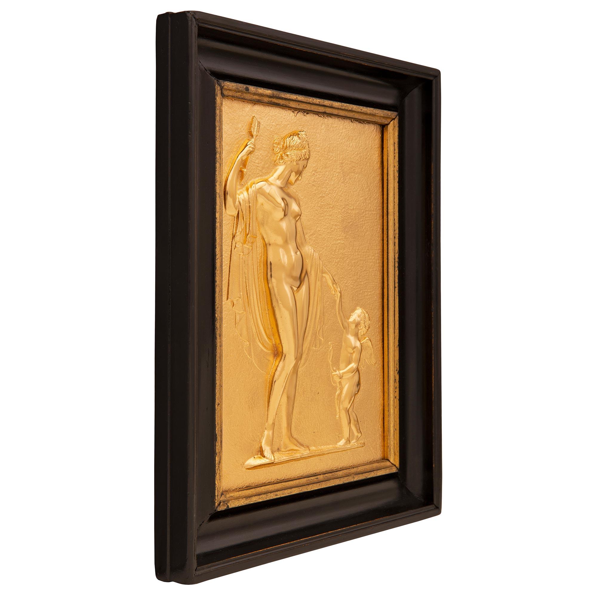Une belle paire de plaques murales décoratives néo-classiques françaises du 19ème siècle en bronze doré et ébène. Chaque décoration murale conserve son cadre rectangulaire d'origine en ébène moucheté avec, au centre, les superbes plaques en bronze
