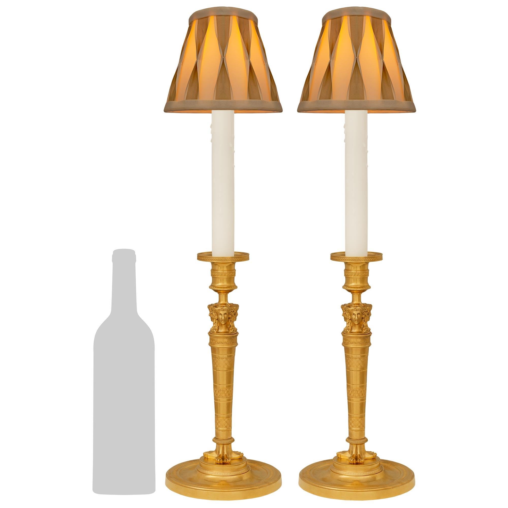 Una pareja única de lámparas de candelero neoclásicas francesas del siglo XIX. Ormolu. Cada una de las elegantísimas lámparas se eleva sobre una base circular de Ormolu bajo el zócalo cónico con una banda decorada con palmeta. El fut central muestra
