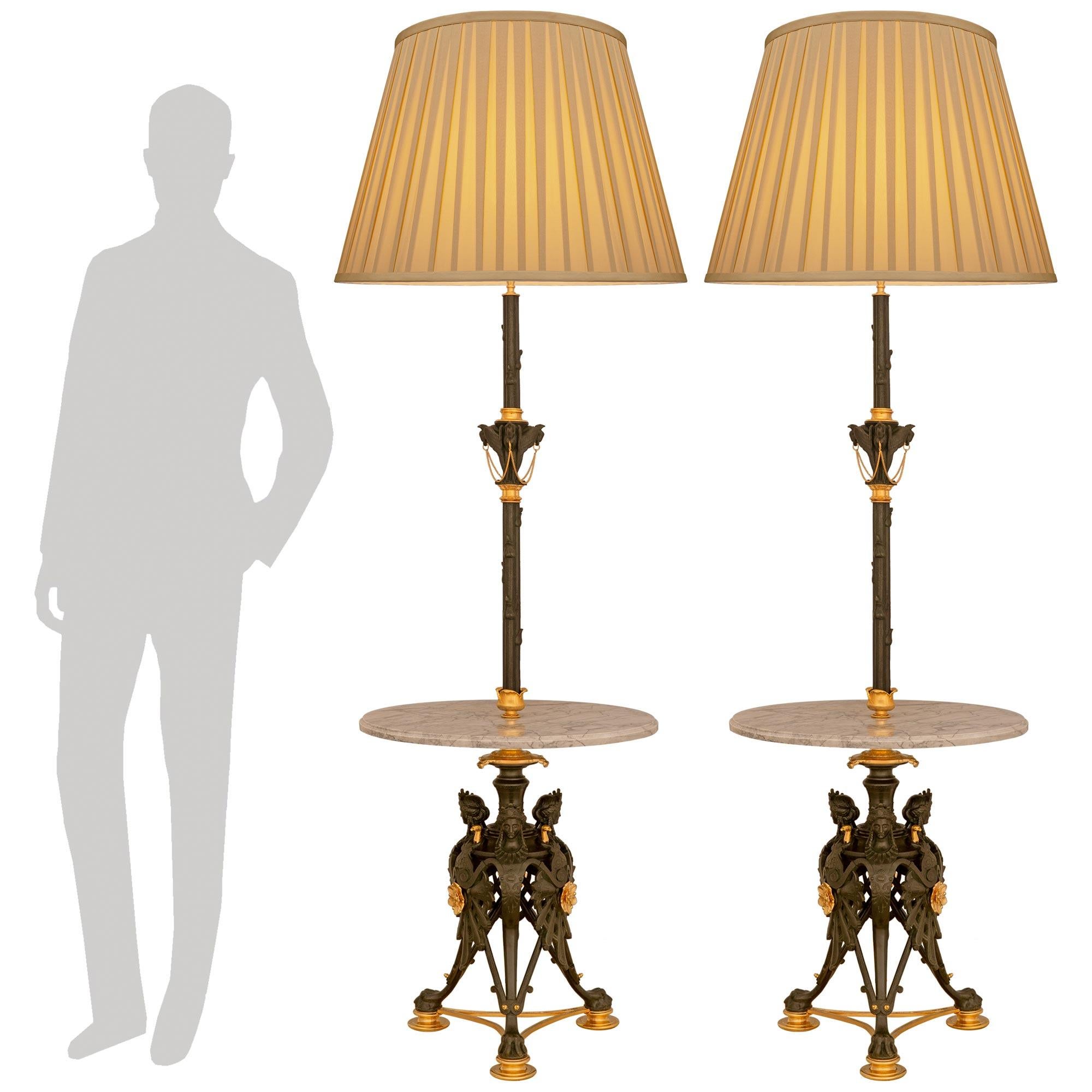 Una coppia rara e unica di tavolini in stile neo-greco francese del XIX secolo. Bronzo patinato, Ormolu e marmo arabescato. Ogni imponente tavolino/lampada da terra è sollevato su tre gambe traforate a 
