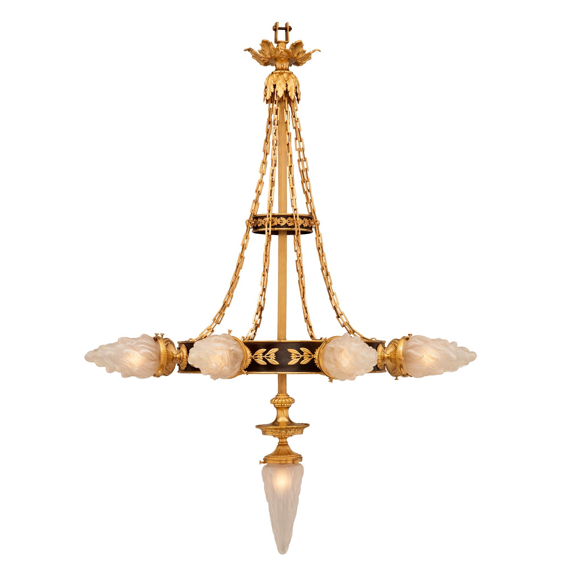 A superb and most decorative pair of French 19th century Neo-Classical patinated bronze, ormolu and frosted glass chandeliers. The chandeliers are centered by their original striking bottom inverted illuminated crystal flames below the lovely fluted
