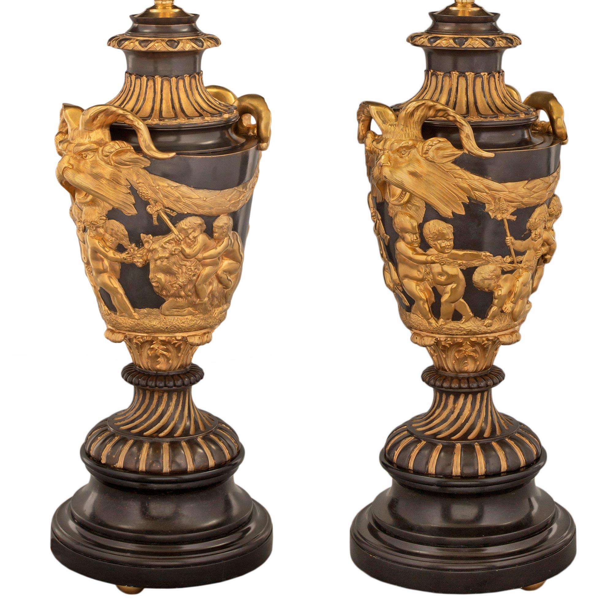 A handsome pair of French 19th century Neo-Classical st. Black Belgian marble, ormolu and patinated bronze lamps in the manner of Clodion after a model by John Flaxman. Each lamp is raised by a beautiful circular mottled black Belgian marble base
