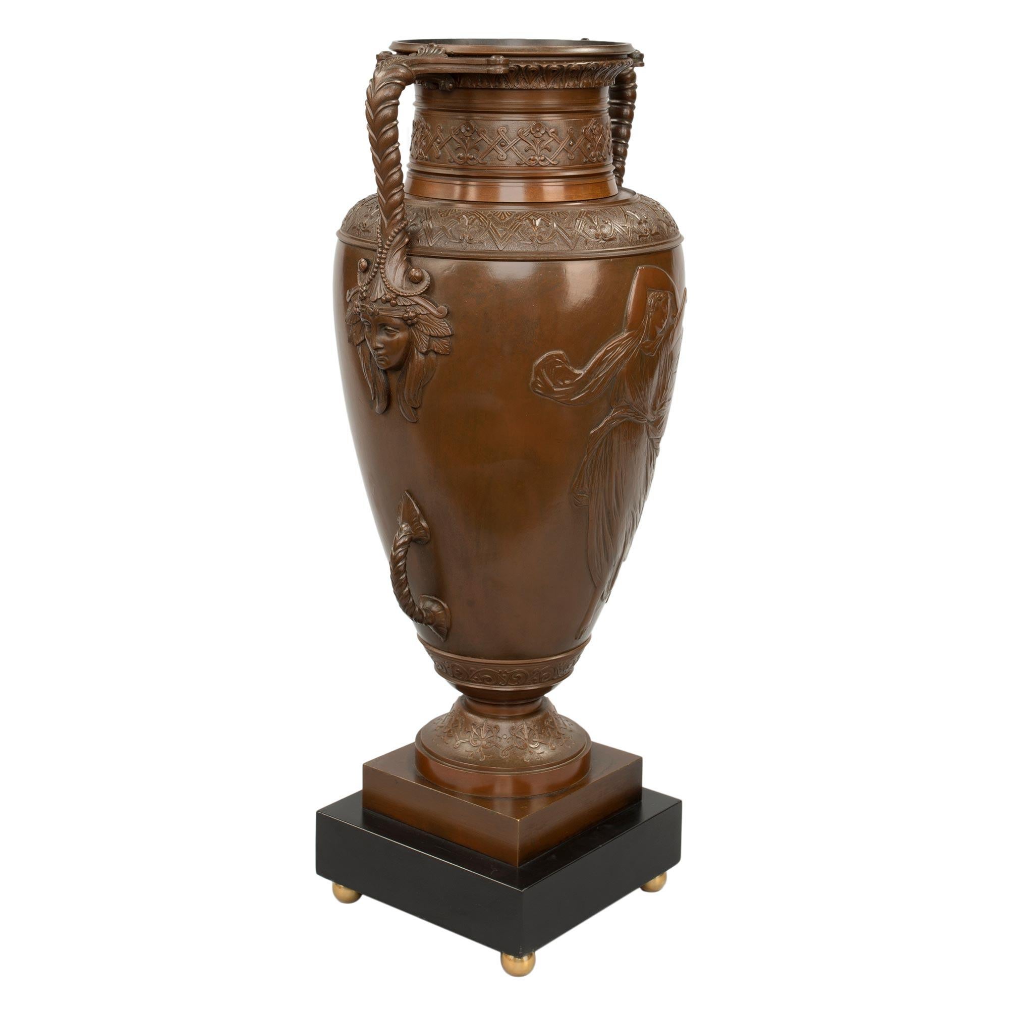Una bella coppia di urne neoclassiche francesi del XIX secolo in bronzo patinato, marmo e ormolu, attribuite a Barbedienne. Ogni urna è sollevata da una base quadrata in marmo nero belga con eleganti piedi a sfera in ormolu. Le urne in bronzo