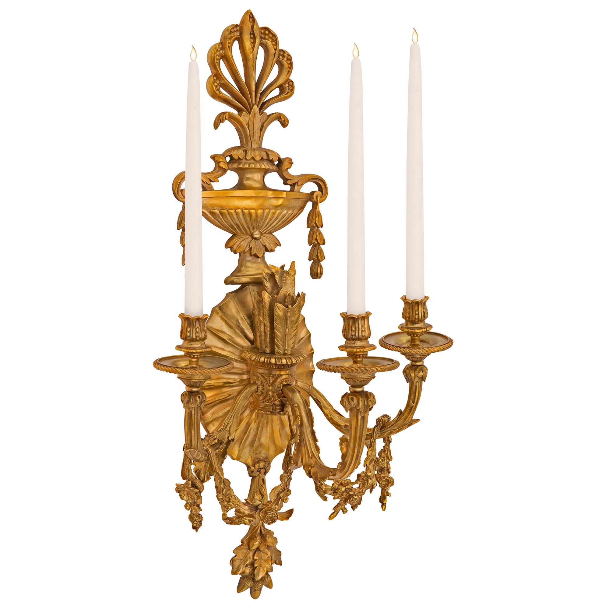 An impressive large scale pair of French 19th century Neo-Classical st. ormolu sconces. Each three arm sconce is centered by charming finely detailed oak leaves and acorns below the beautiful reeded sunburst designed backplate. The elegantly curved
