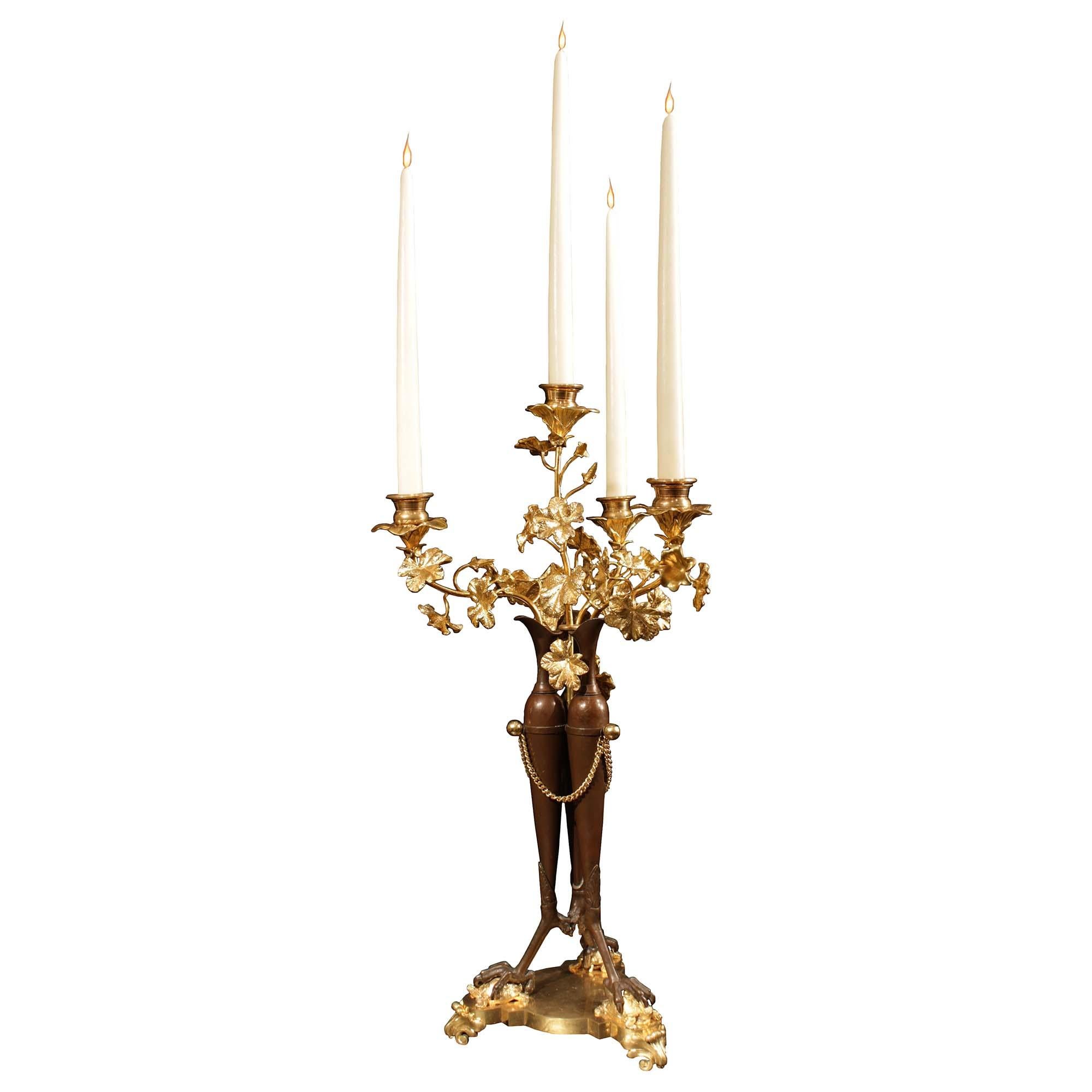 A handsome pair of French 19th century Neo-Classical st. patinated bronze and ormolu four arm candelabras. Each candelabra is set on a thick triangular base with convex mottled sides then raised on three acanthus leaf feet below grand claws holding