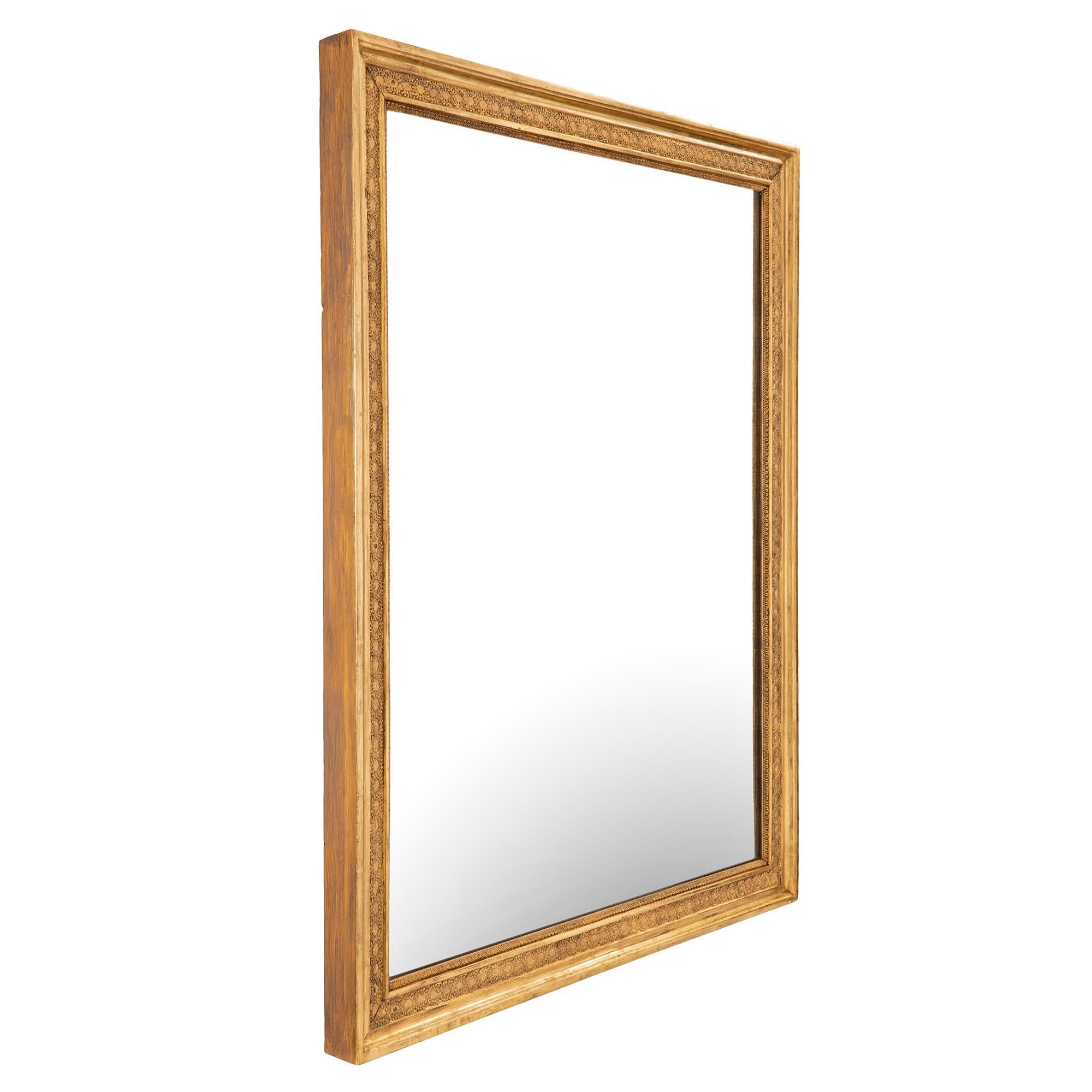 Un'elegantissima coppia di specchi in legno dorato neoclassico francese del XIX secolo. I piatti a specchio sono incorniciati da un raffinato motivo Coeur de Rai con corone di alloro intrecciate che si estendono lungo il bordo screziato. Con tutte